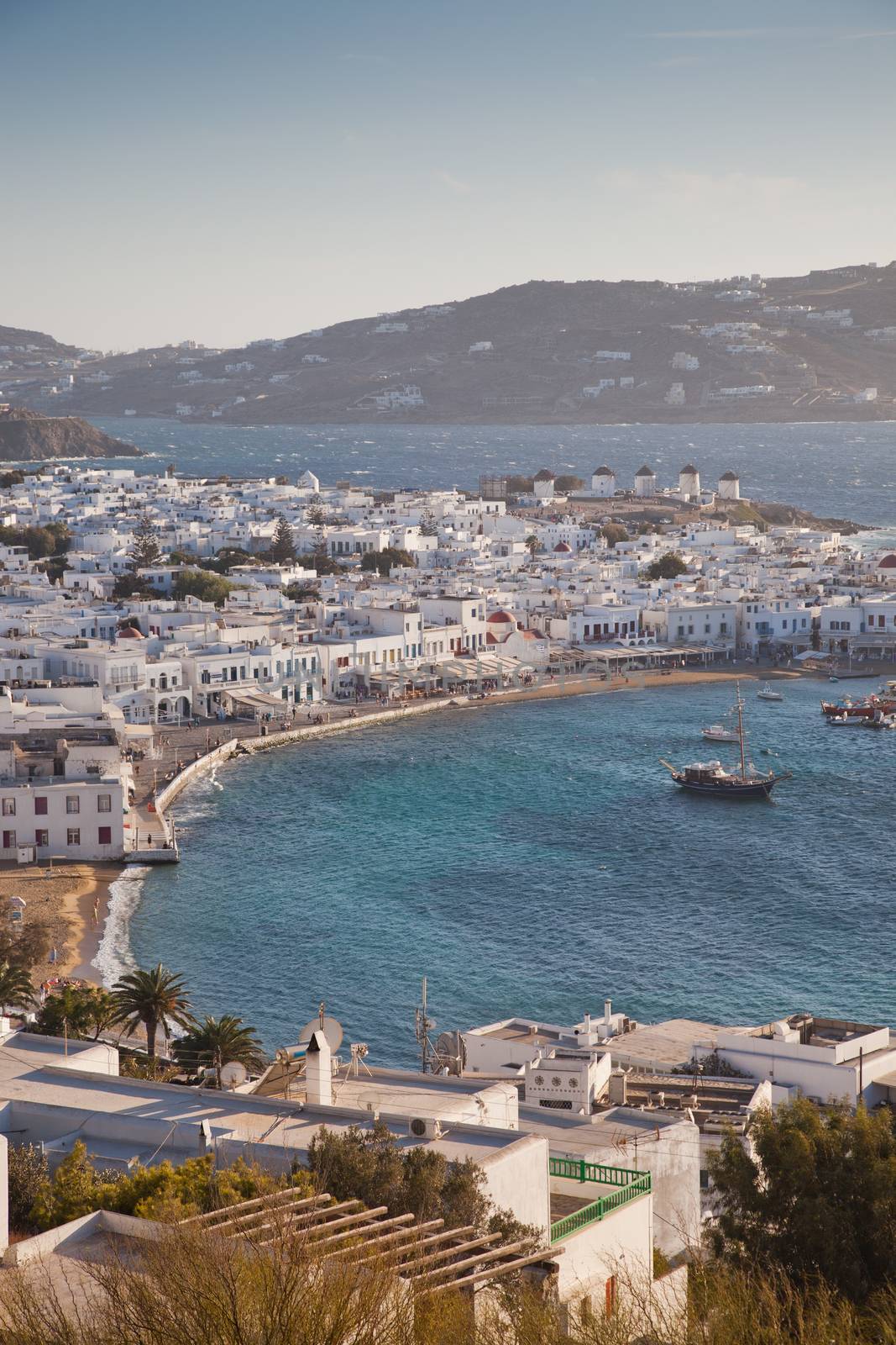 panoramic view of the Mykonos town harbor with famous windmills from the above hills on a sunny summer day, Mykonos, Cyclades, Greece 