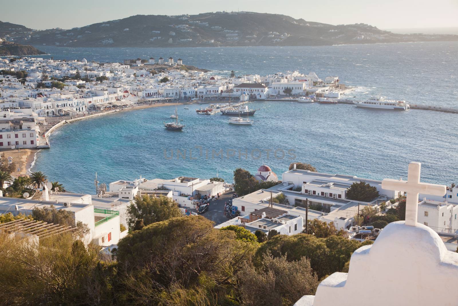 panoramic view of the Mykonos town harbor with famous windmills from the above hills on a sunny summer day, Mykonos, Cyclades, Greece 