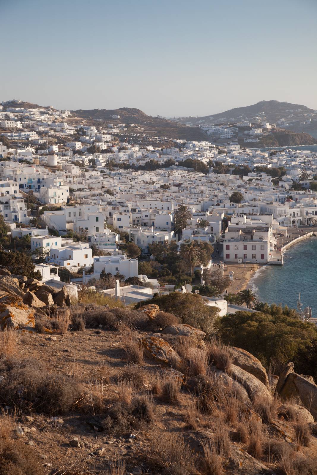 panoramic view of the Mykonos town harbor with famous windmills from the above hills on a sunny summer day, Mykonos, Cyclades, Greece 