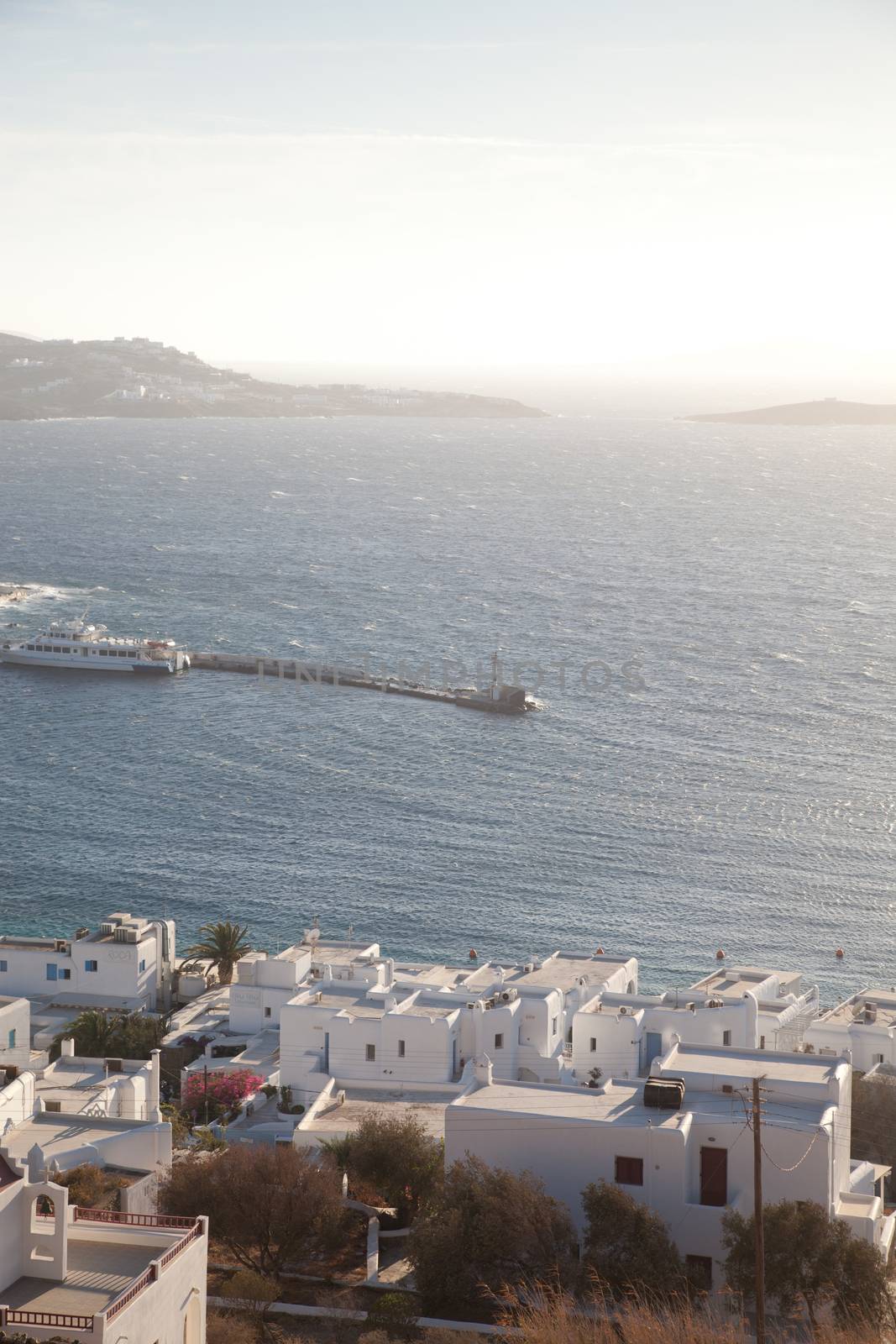 panoramic view of the Mykonos town harbor with famous windmills from the above hills on a sunny summer day, Mykonos, Cyclades, Greece 