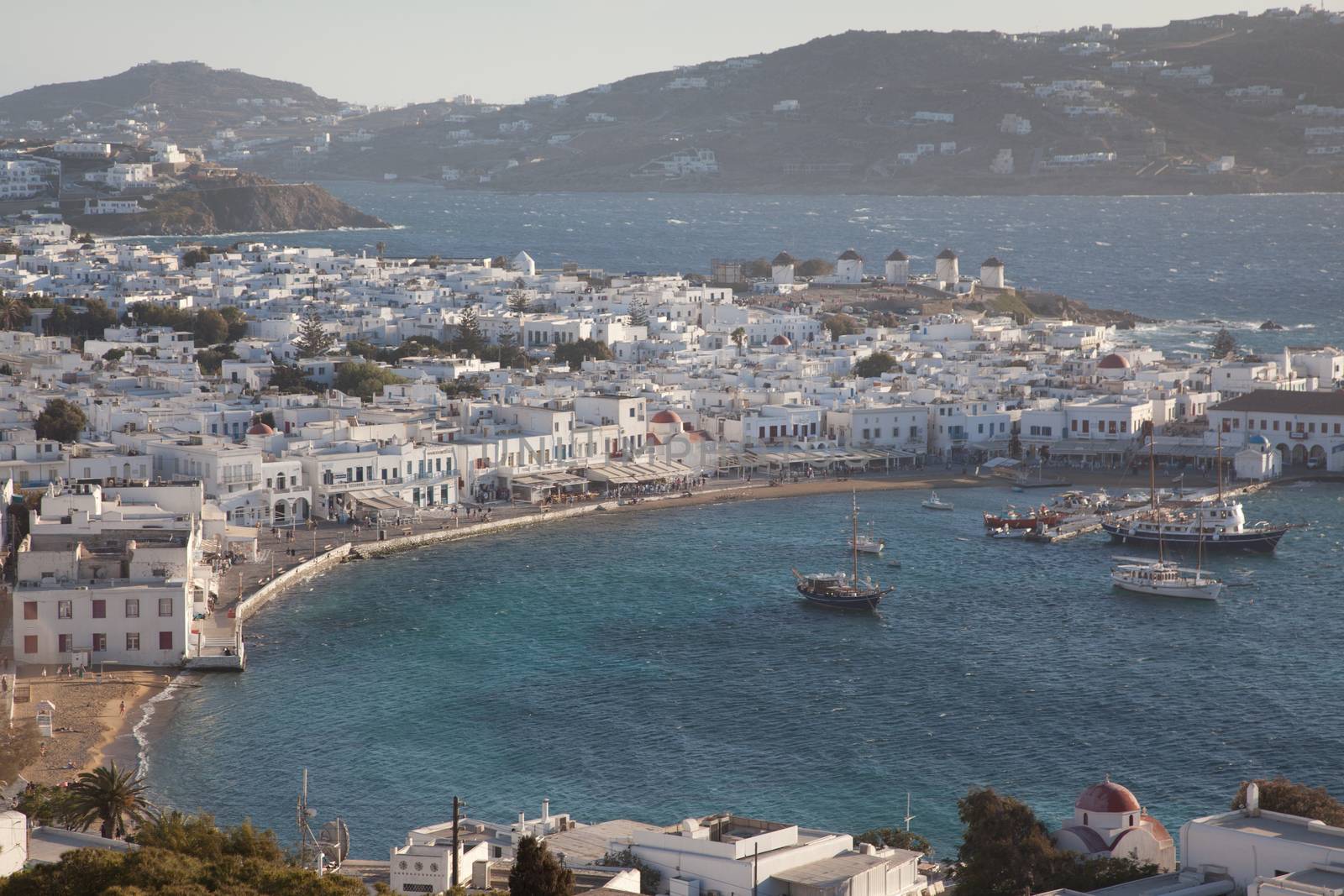 panoramic view of the Mykonos town harbor with famous windmills from the above hills on a sunny summer day, Mykonos, Cyclades, Greece 