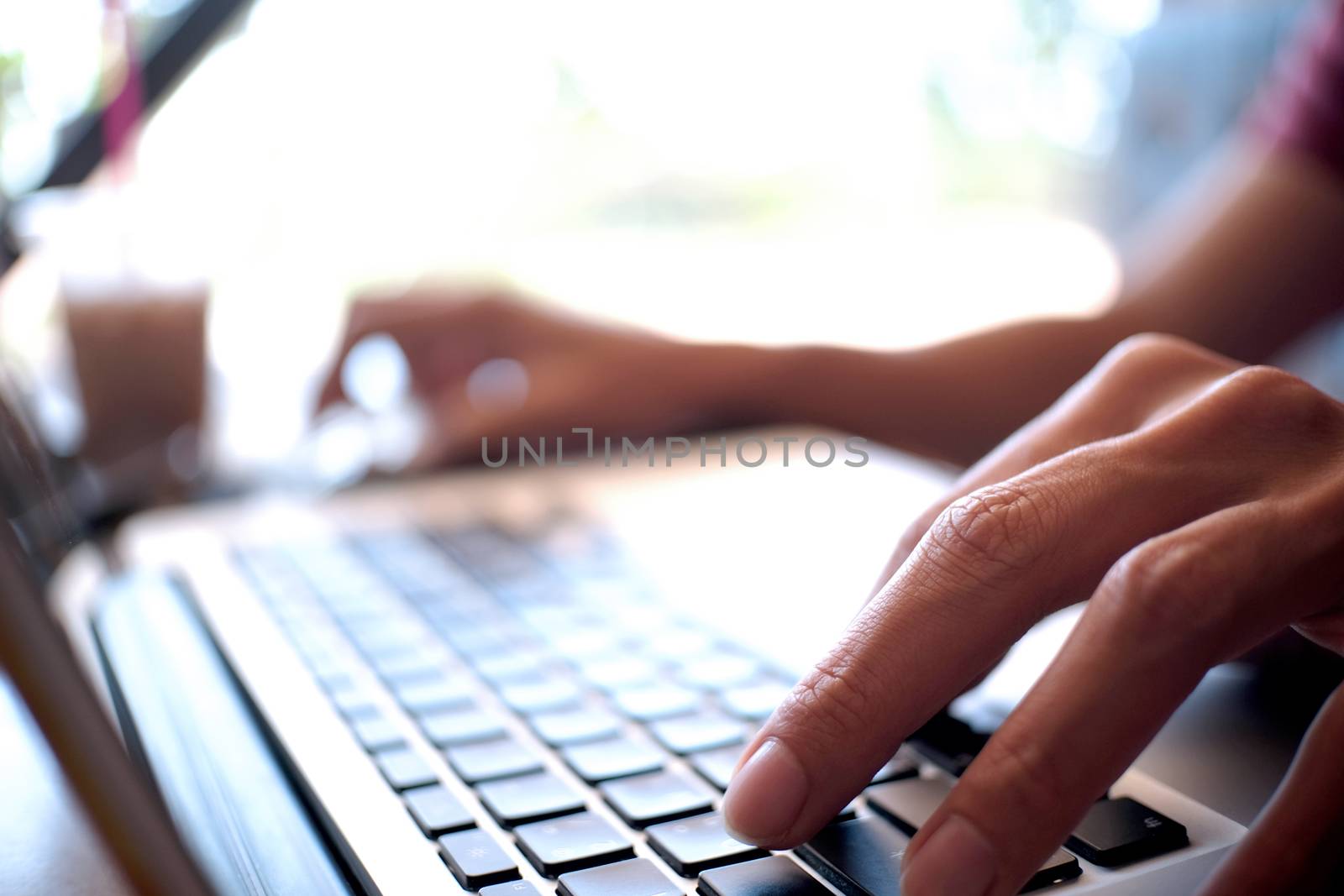 Man working by using a laptop computer on wooden table. Hands ty by peandben