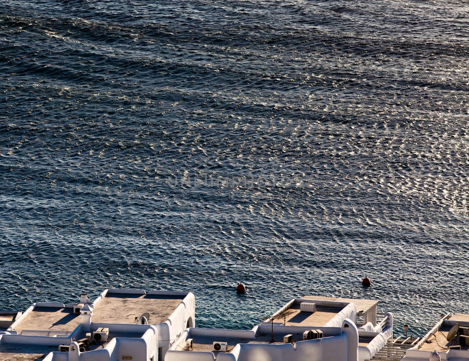 panoramic view of the Mykonos town harbor with famous windmills from the above hills on a sunny summer day, Mykonos, Cyclades, Greece 