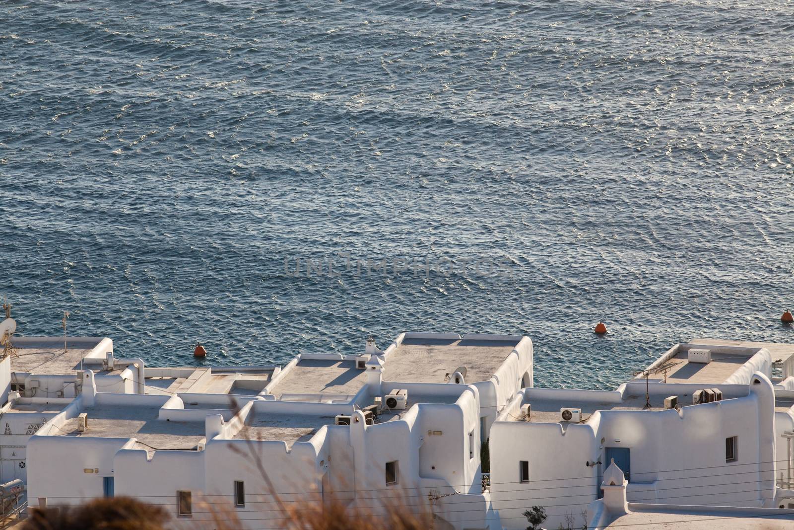 panoramic view of the Mykonos town harbor with famous windmills from the above hills on a sunny summer day, Mykonos, Cyclades, Greece 