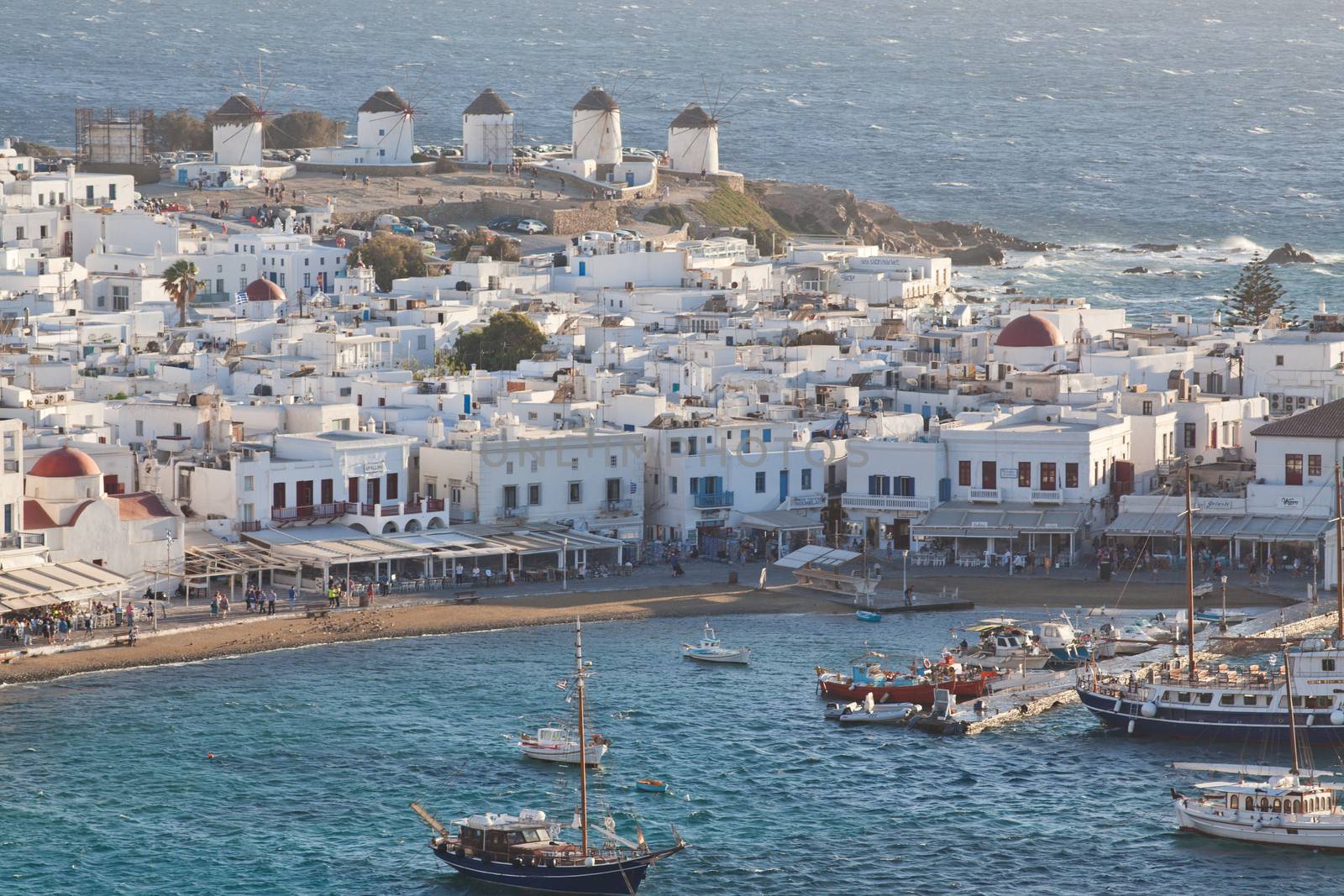 panoramic view of the Mykonos town harbor with famous windmills from the above hills on a sunny summer day, Mykonos, Cyclades, Greece 