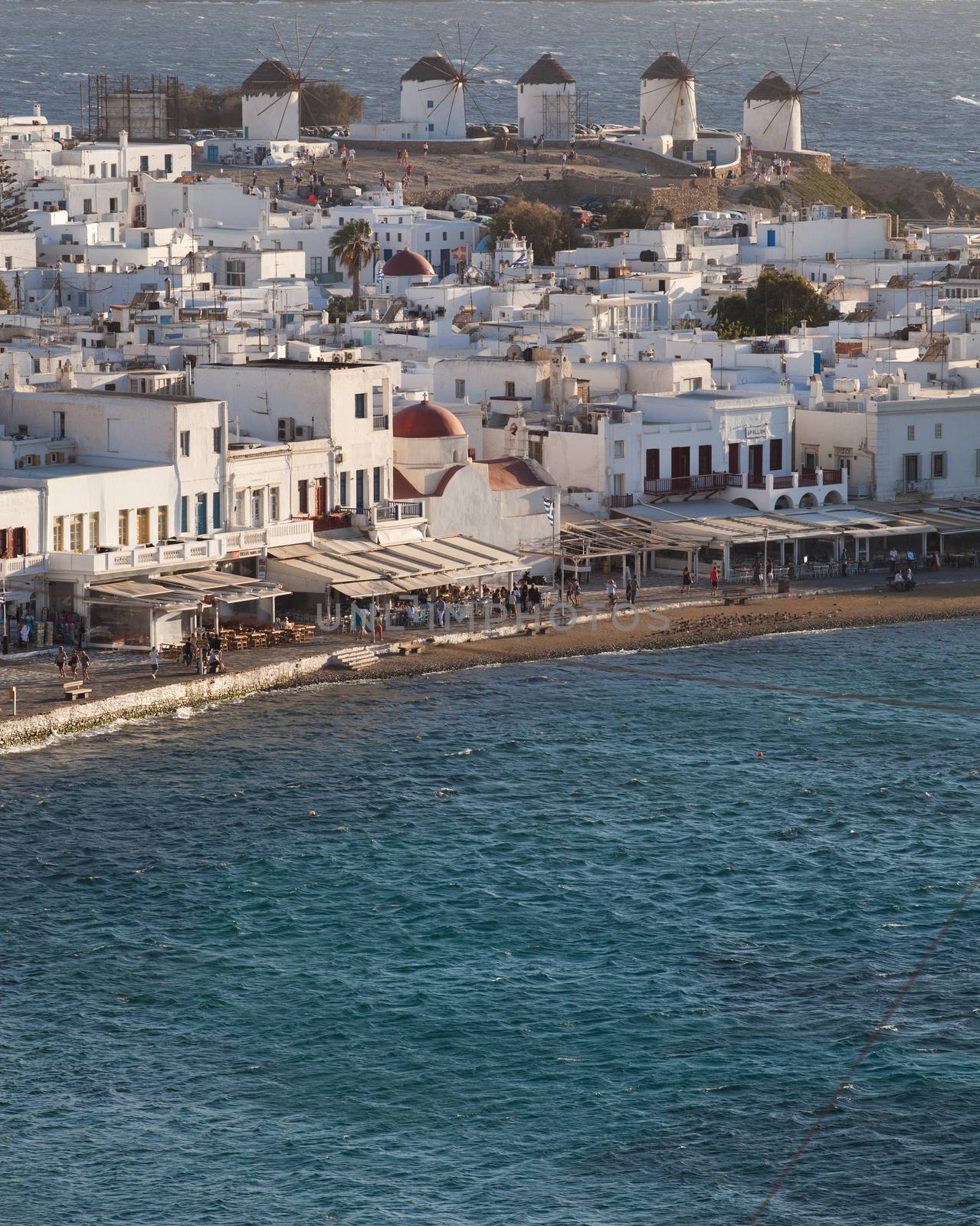 panoramic view of the Mykonos town harbor with famous windmills from the above hills on a sunny summer day, Mykonos, Cyclades, Greece 