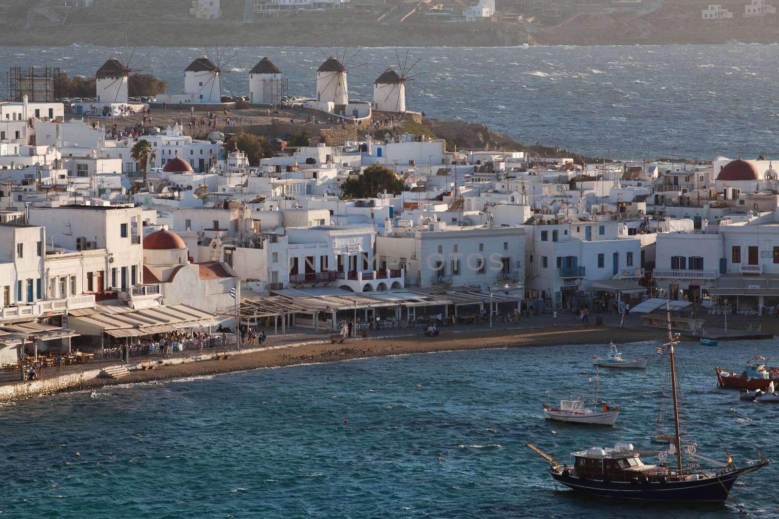 panoramic view of the Mykonos town harbor with famous windmills from the above hills on a sunny summer day, Mykonos, Cyclades, Greece 