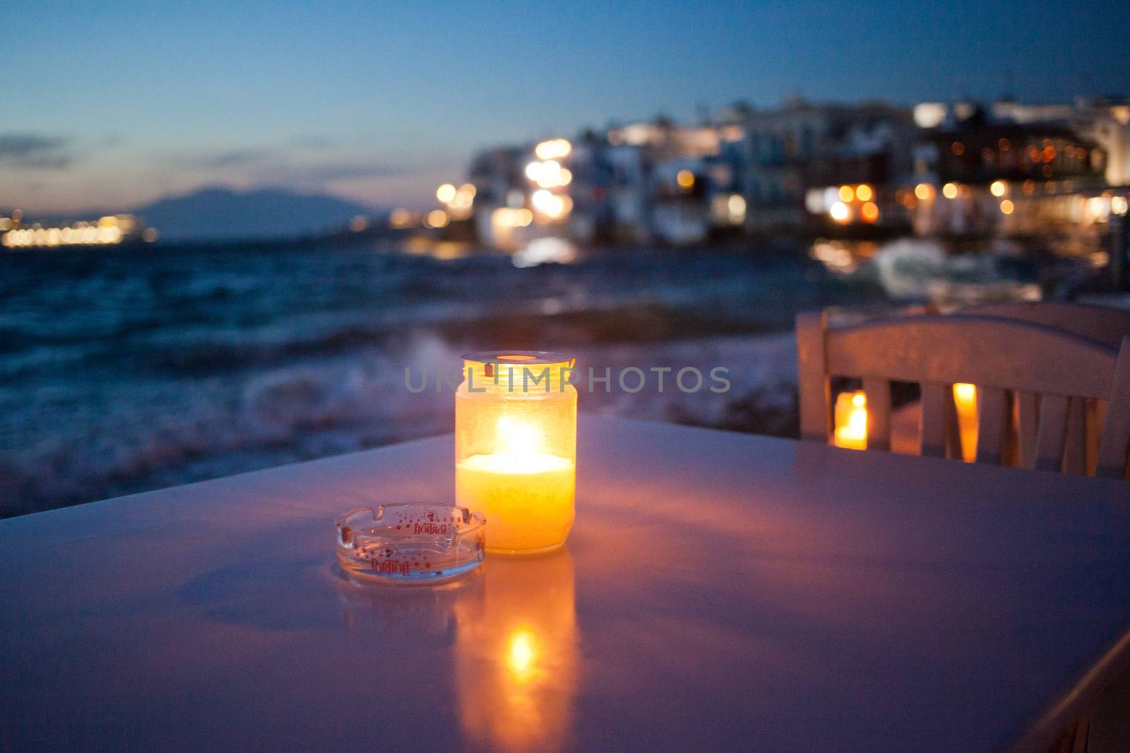 romantic table with burning candle by the sea at night