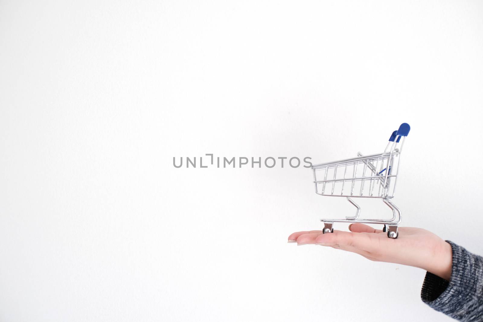 Woman hand forefinger pushing small shopping cart with Internet online shopping concept