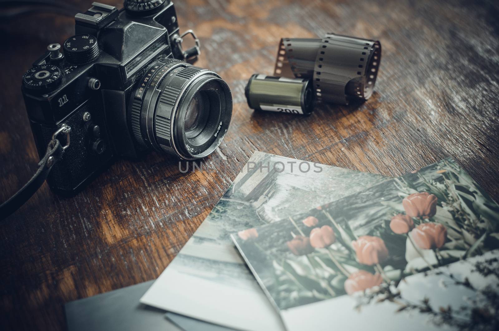 Retro photo camera, film and old photos on the table.