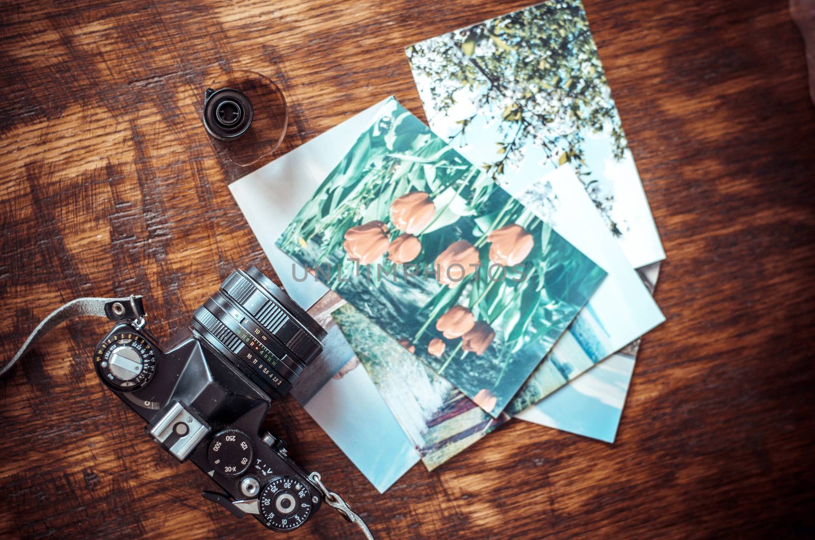 Old photo film roll and retro camera on desk.