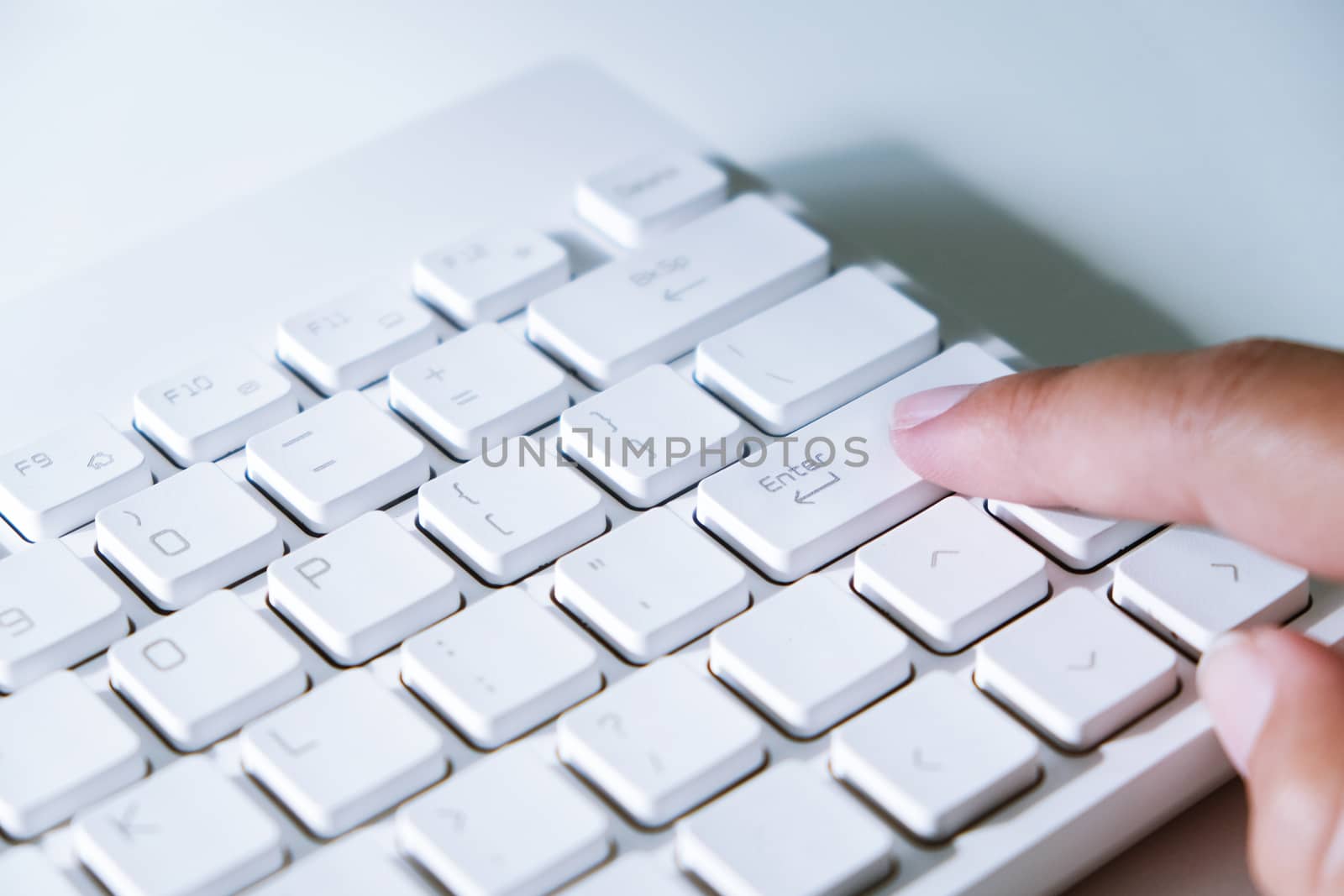 Close up female finger on the enter key. by peandben