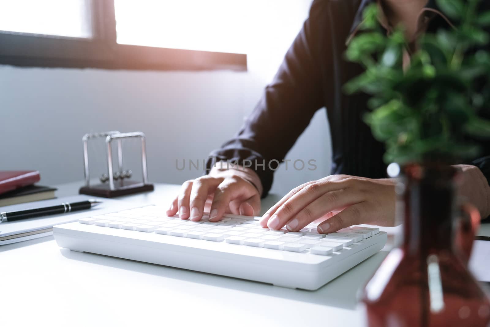 Woman working by using a laptop computer on wooden table. Hands typing on a keyboard.