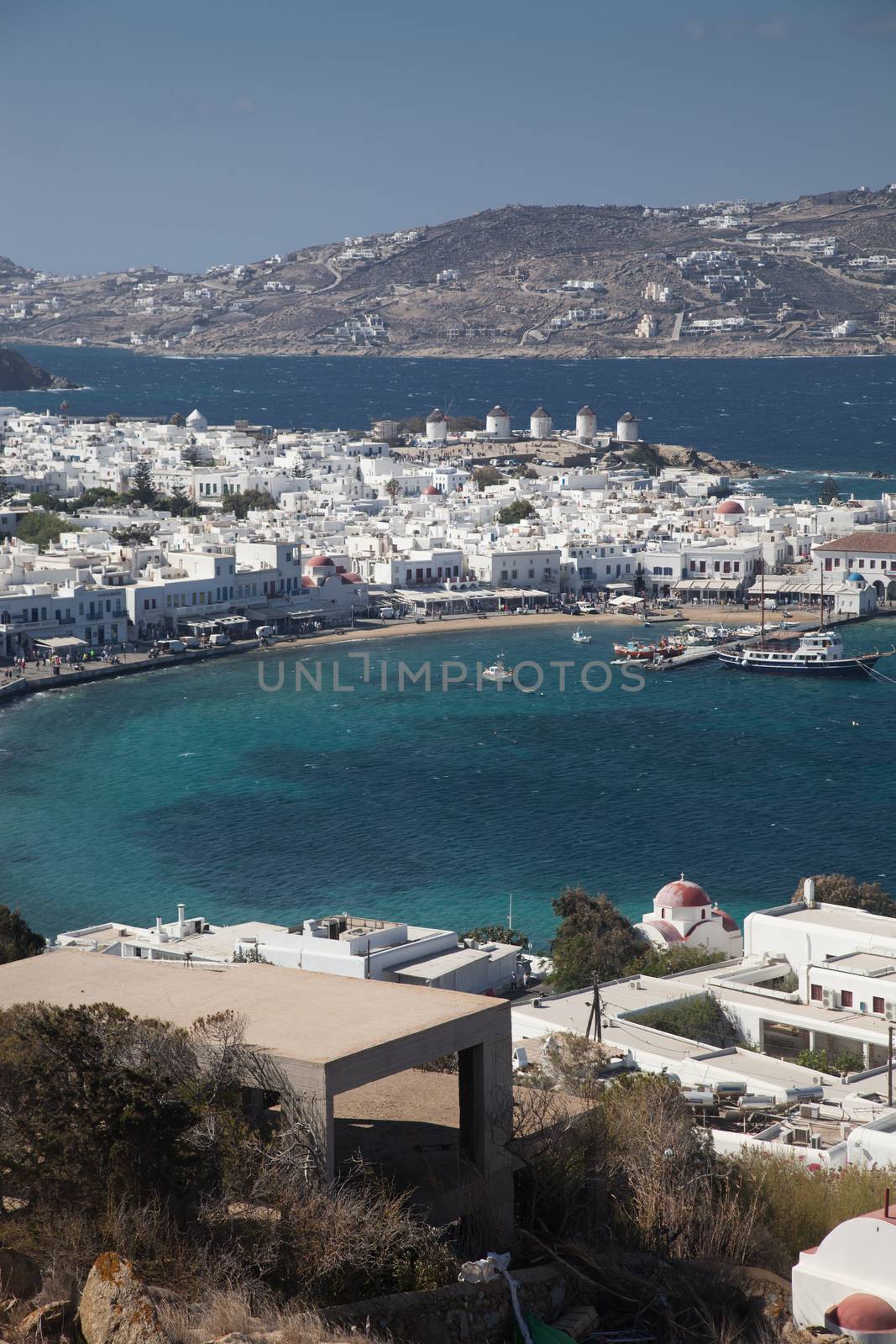 panoramic view of the Mykonos town harbor with famous windmills from the above hills on a sunny summer day, Mykonos, Cyclades, Greece 