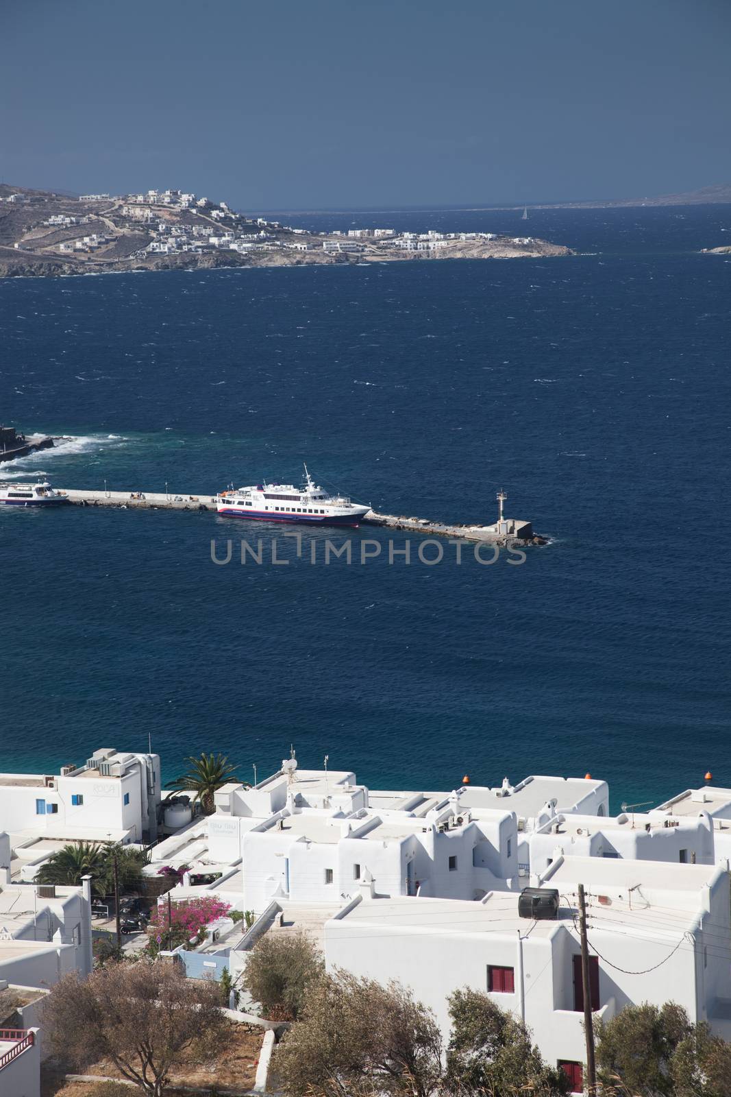 panoramic view of the Mykonos town harbor with famous windmills from the above hills on a sunny summer day, Mykonos, Cyclades, Greece 