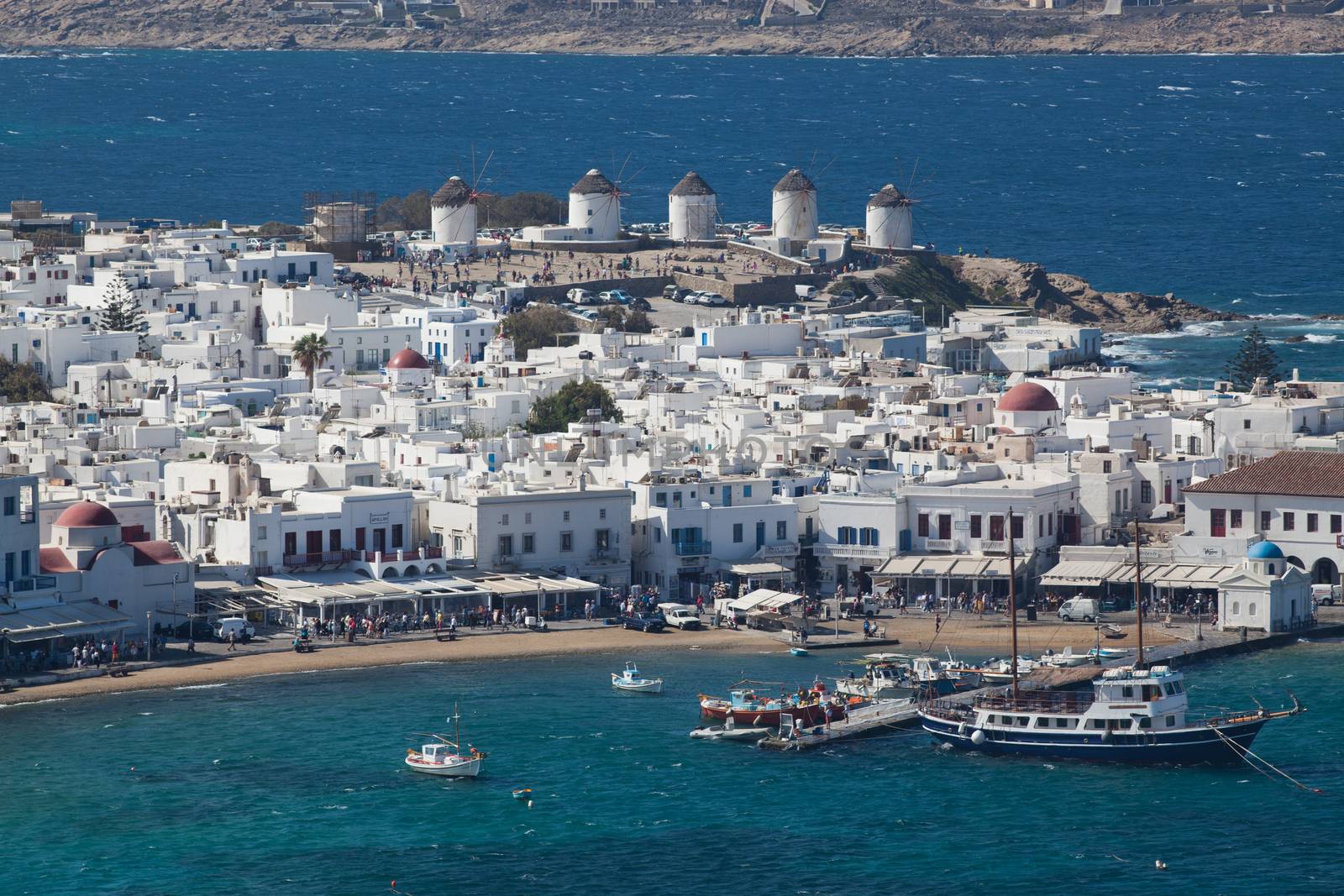 panoramic view of the Mykonos town harbor with famous windmills from the above hills on a sunny summer day, Mykonos, Cyclades, Greece 