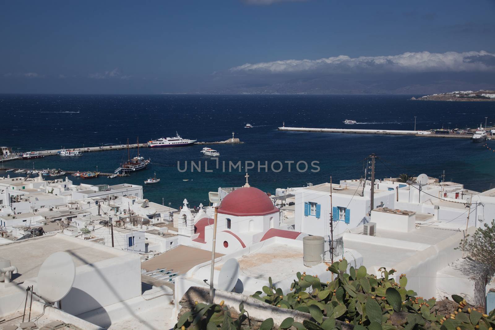 panoramic view of the Mykonos town harbor with famous windmills from the above hills on a sunny summer day, Mykonos, Cyclades, Greece 