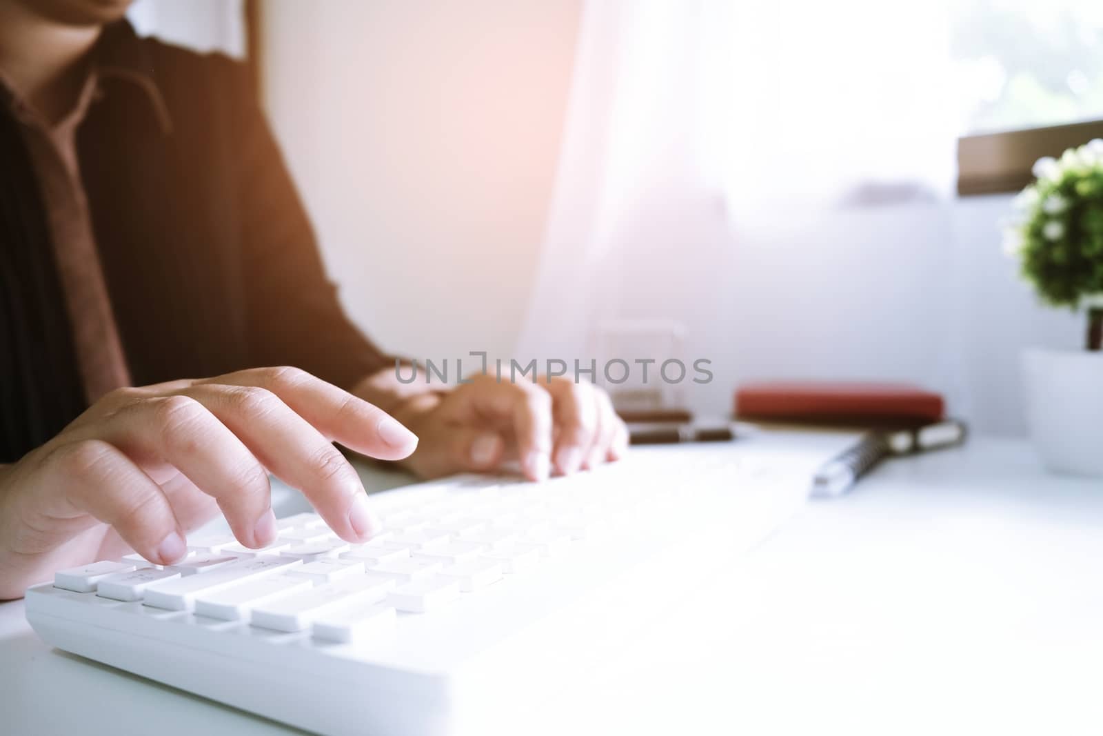 Woman working by using a laptop computer on wooden table. Hands typing on a keyboard.