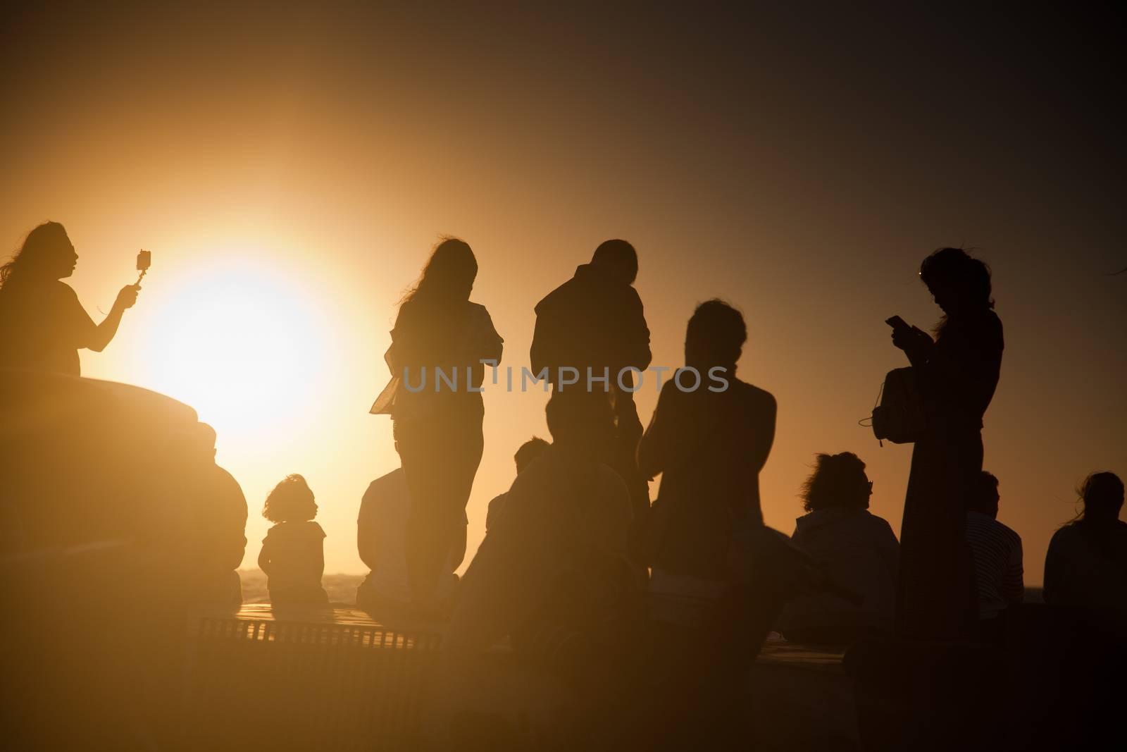 silhouettes of people taking pictures with smartphones by melis