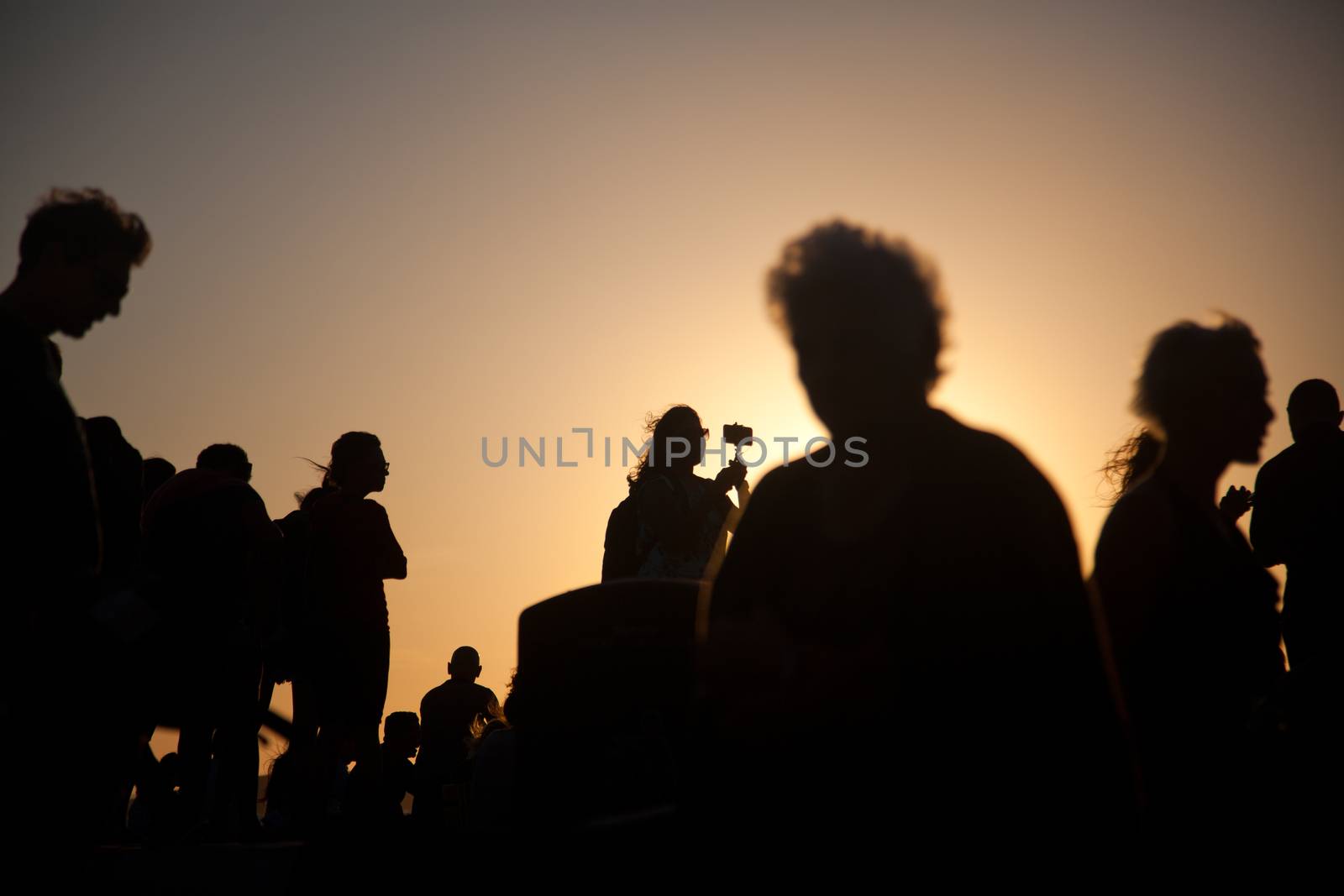 silhouettes of people taking pictures with smartphones by melis