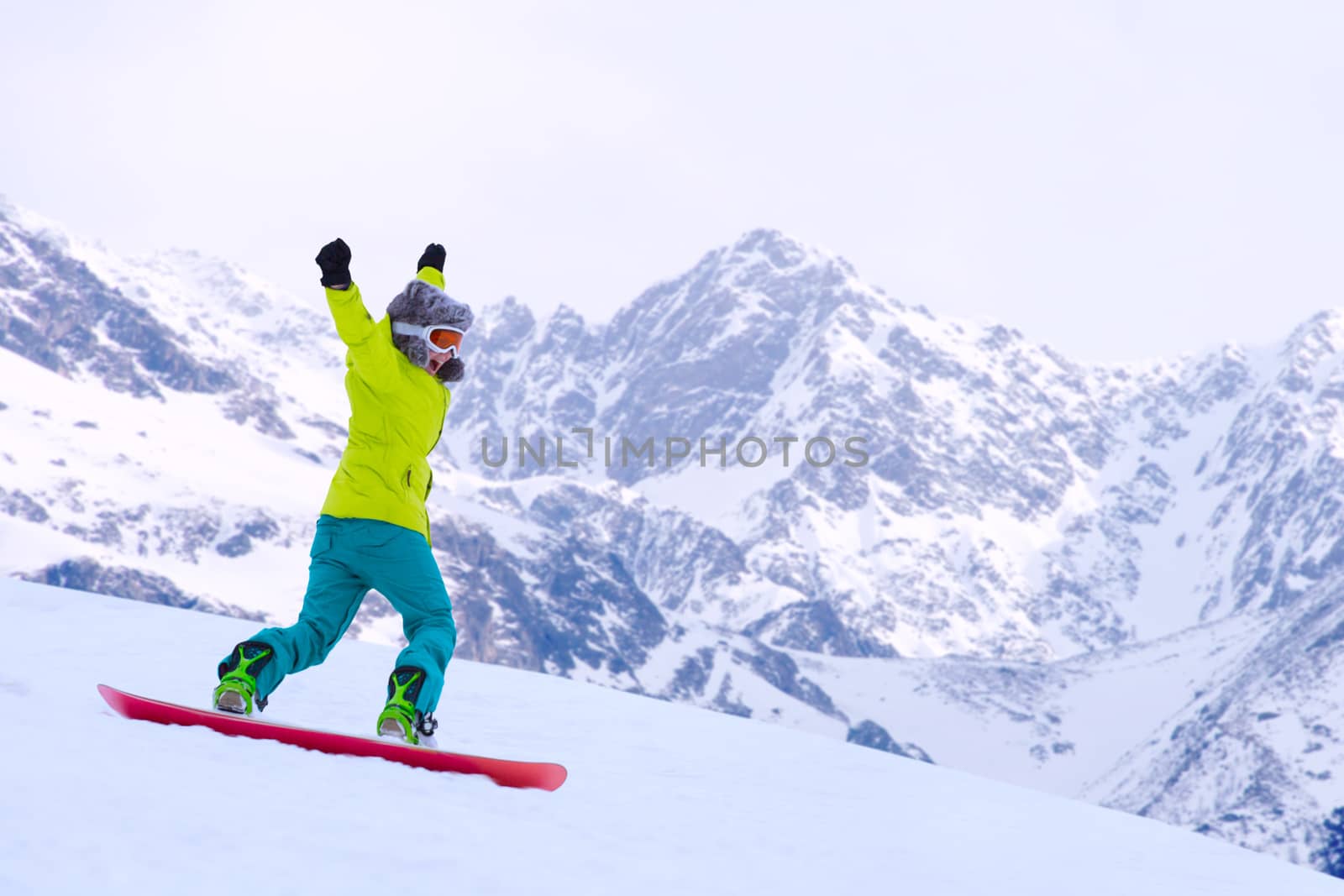 Girl snowboarder running down the slope in Alpine mountains. Winter sport and recreation, leisure outdoor activities. Image of excited screaming young woman enjoyment concept