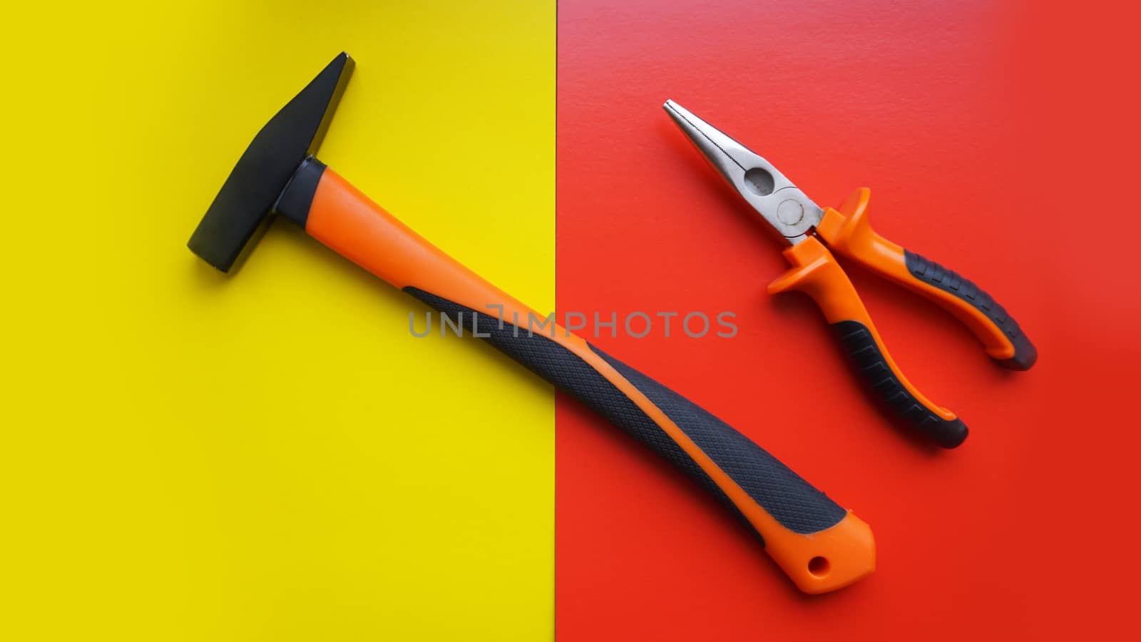 Tools worker, hammer, pliers on bright yellow and red background, top view by natali_brill
