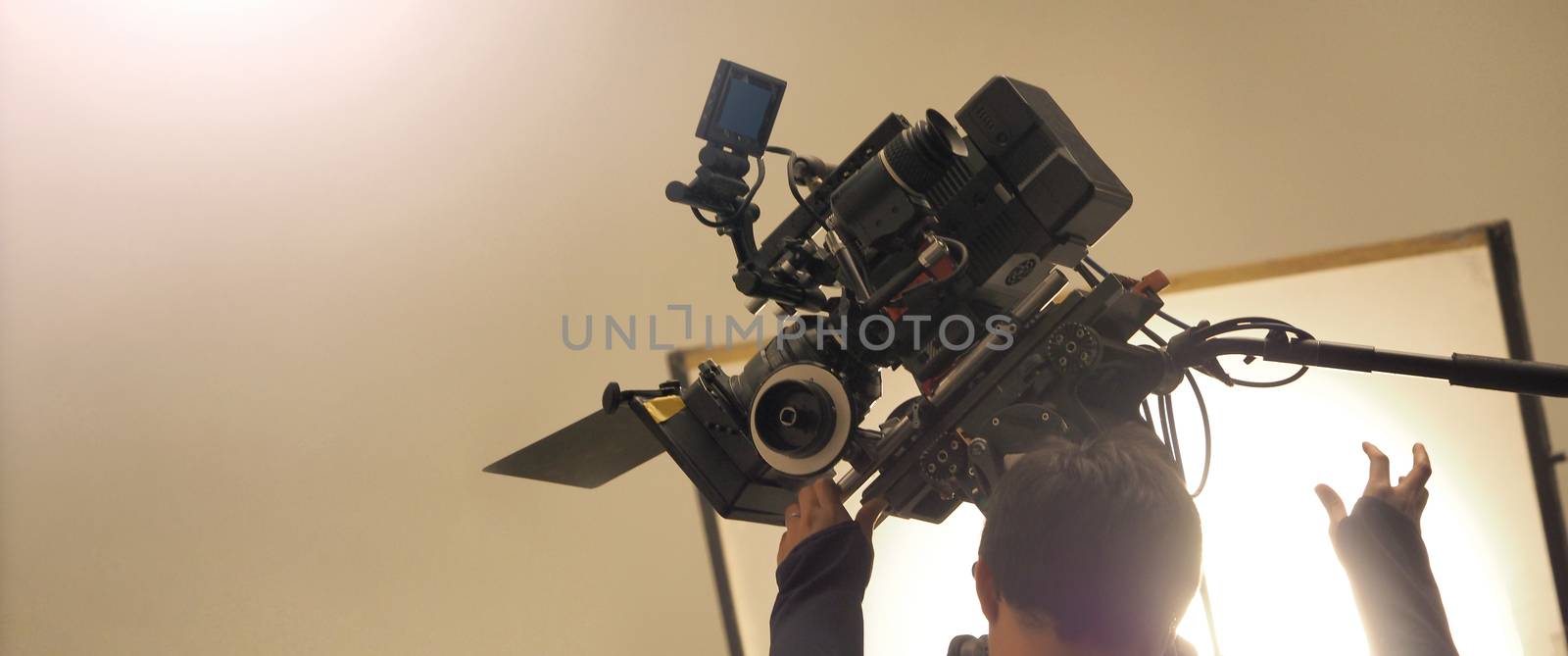 Behind the shooting or filming video movie and film production crew team setting up camera on tripod and professional equipment in studio for offline tv commercial or online web film recording.