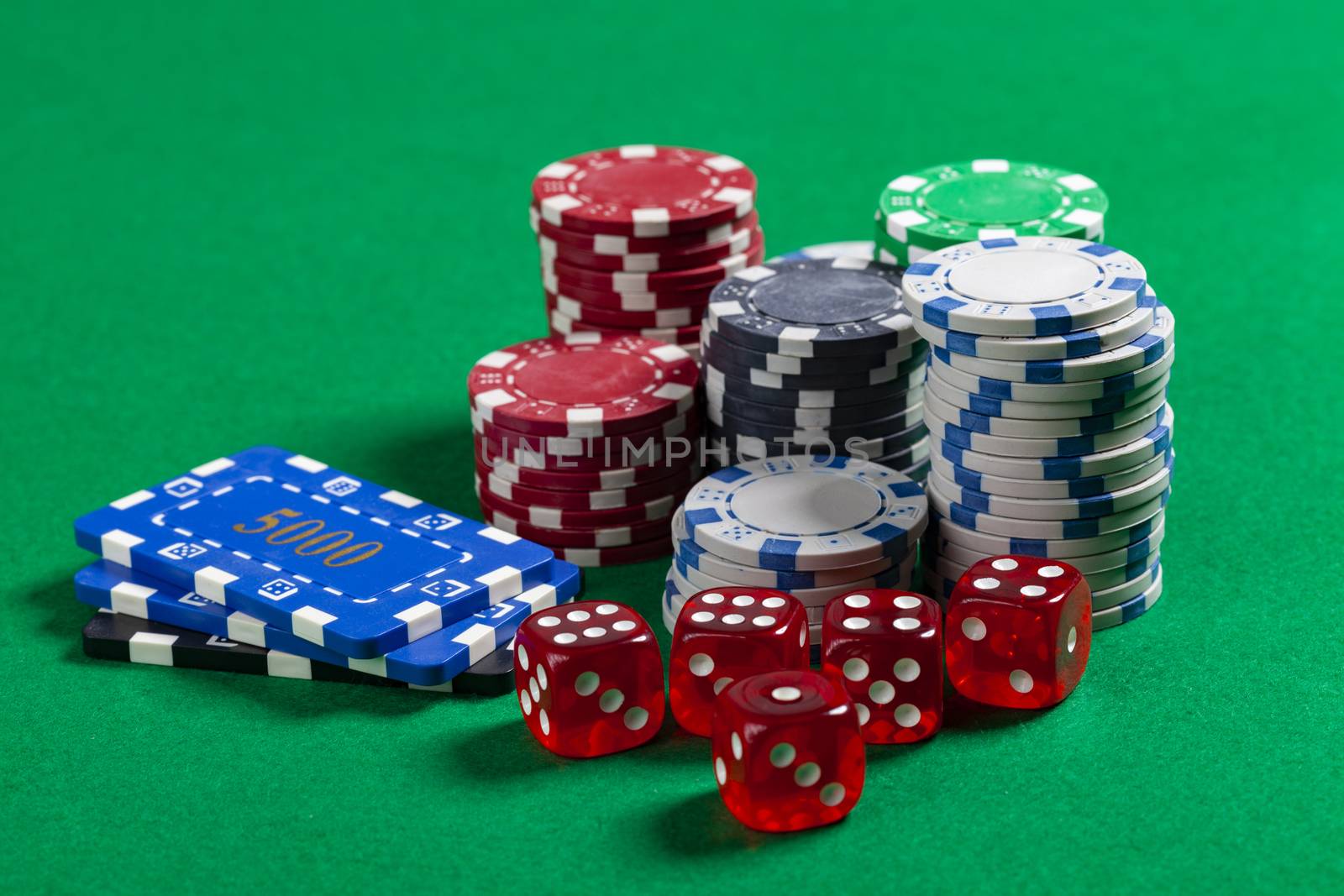 Pile of Casino Chips and Red Dice on Green Poker Table