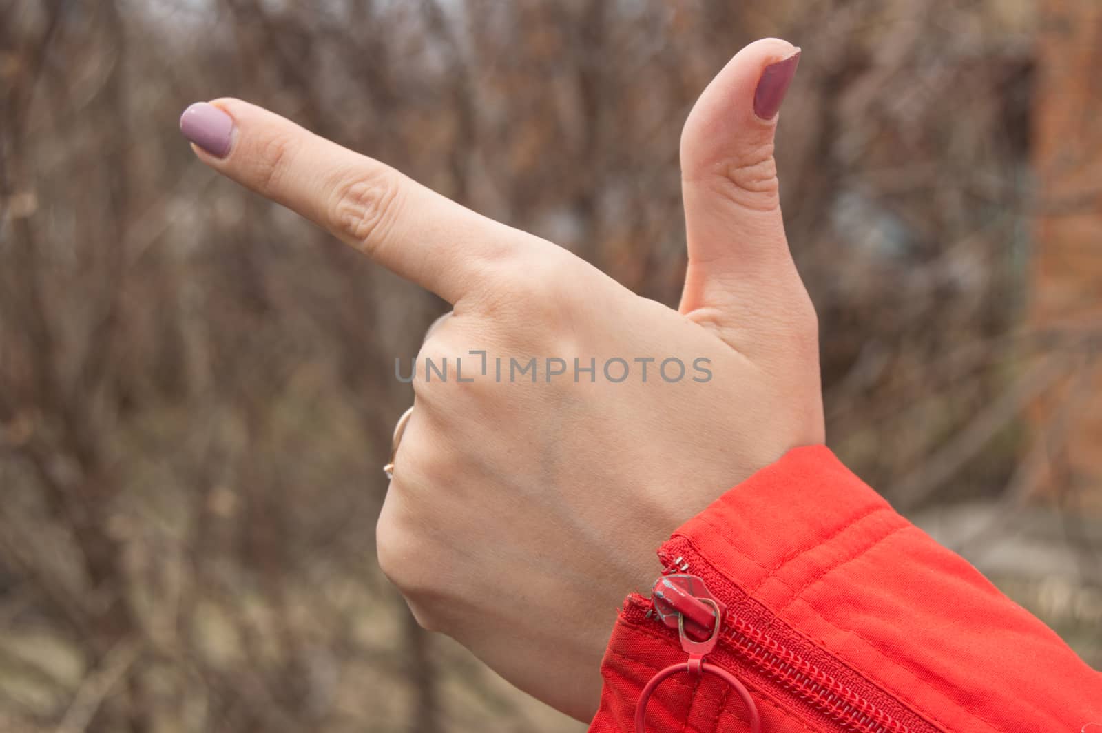 Woman hand making the sign of the index finger showing direction outdoors.