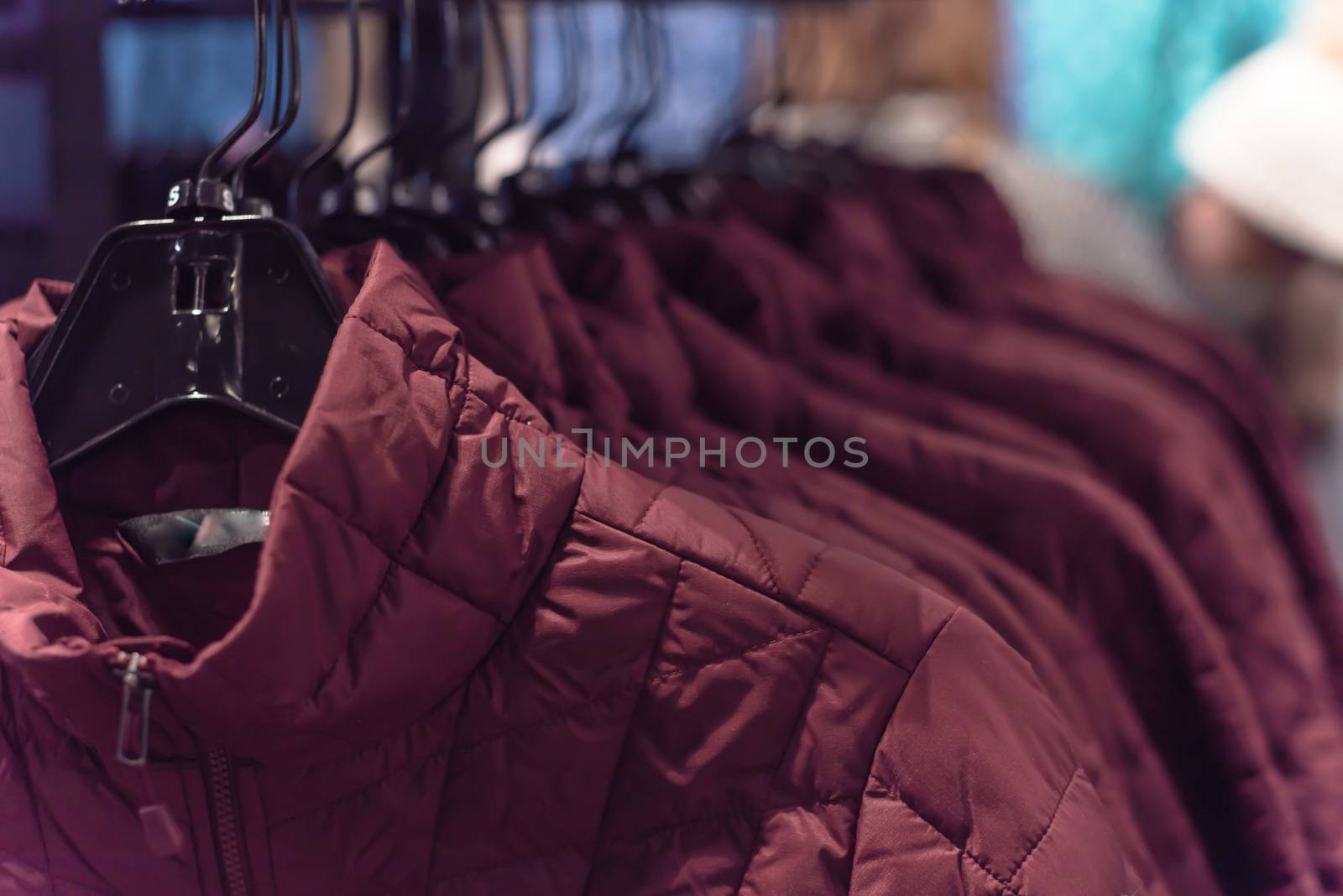 Close-up winter down on clothes rack at American outdoor clothing shop. Insulated fashionable jacket with zip pocket.