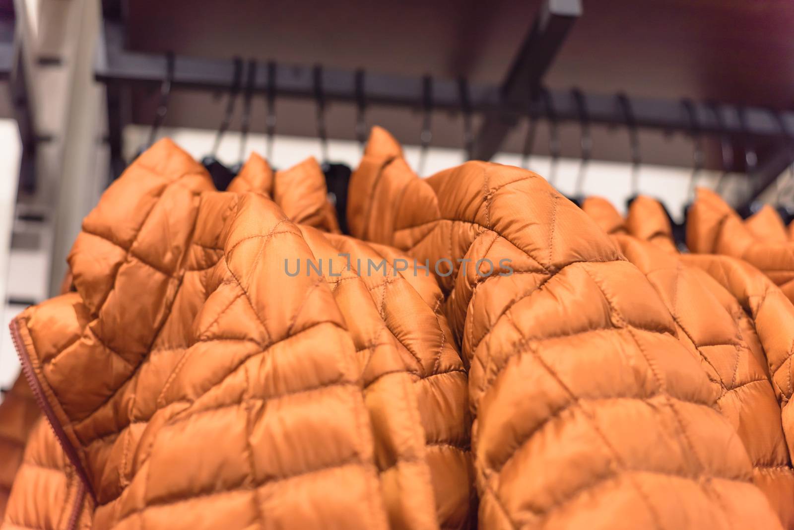 Close-up winter down on clothes rack at American outdoor clothing shop. Insulated fashionable jacket with zip pocket.