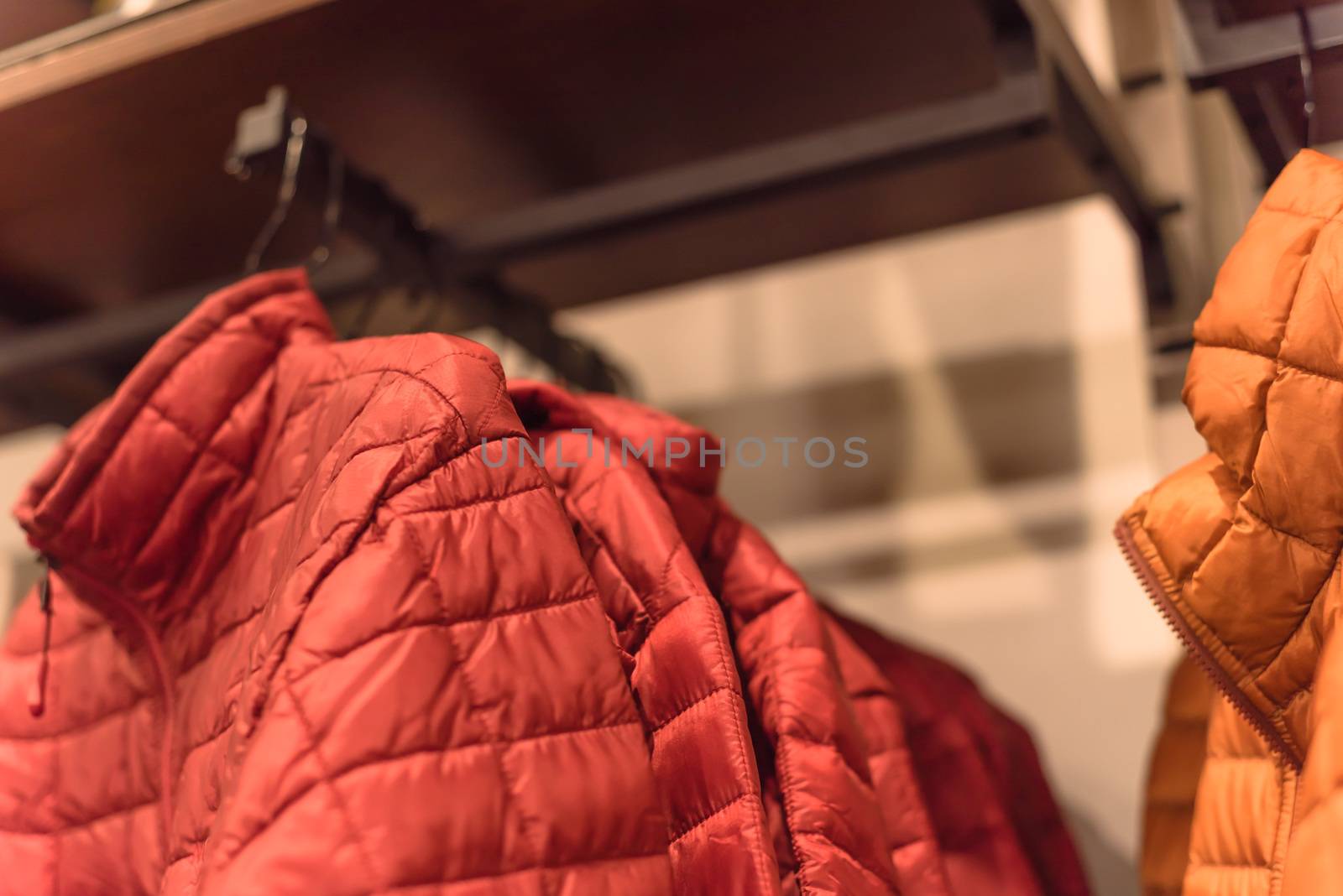 Close-up winter down on clothes rack at American outdoor clothing shop. Insulated fashionable jacket with zip pocket.