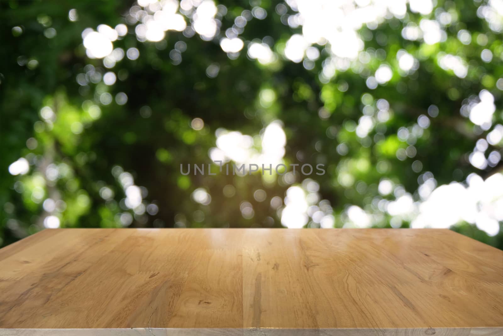 Image of dark wooden table in front of abstract blurred background of outdoor garden lights. can be used for display or montage your products.Mock up for display of product.