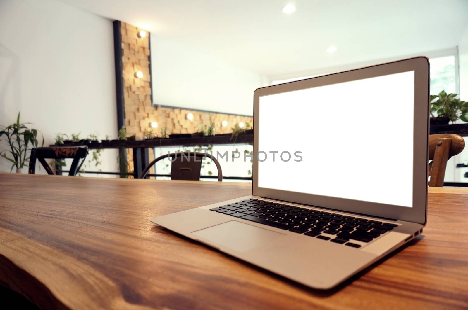 Laptop with Mock up blank screen on wooden table in front of coffeeshop cafe space for text. product display montage- technology concept.