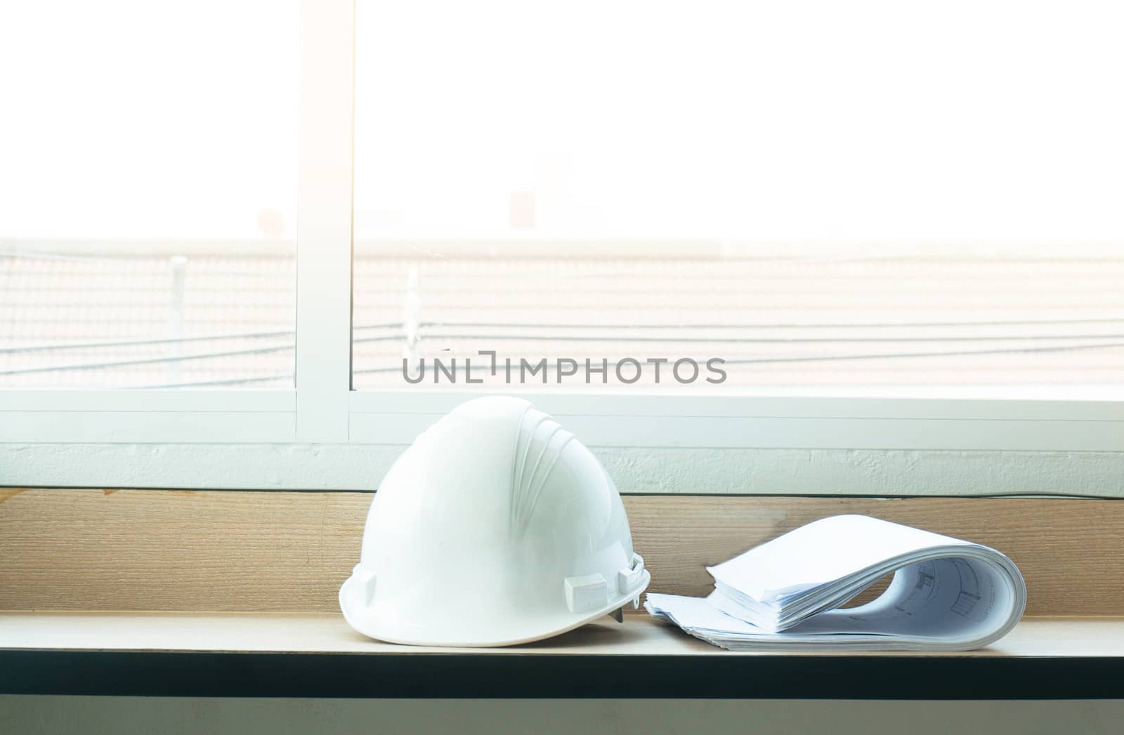 Construction drawing blueprints and white hard hat on table