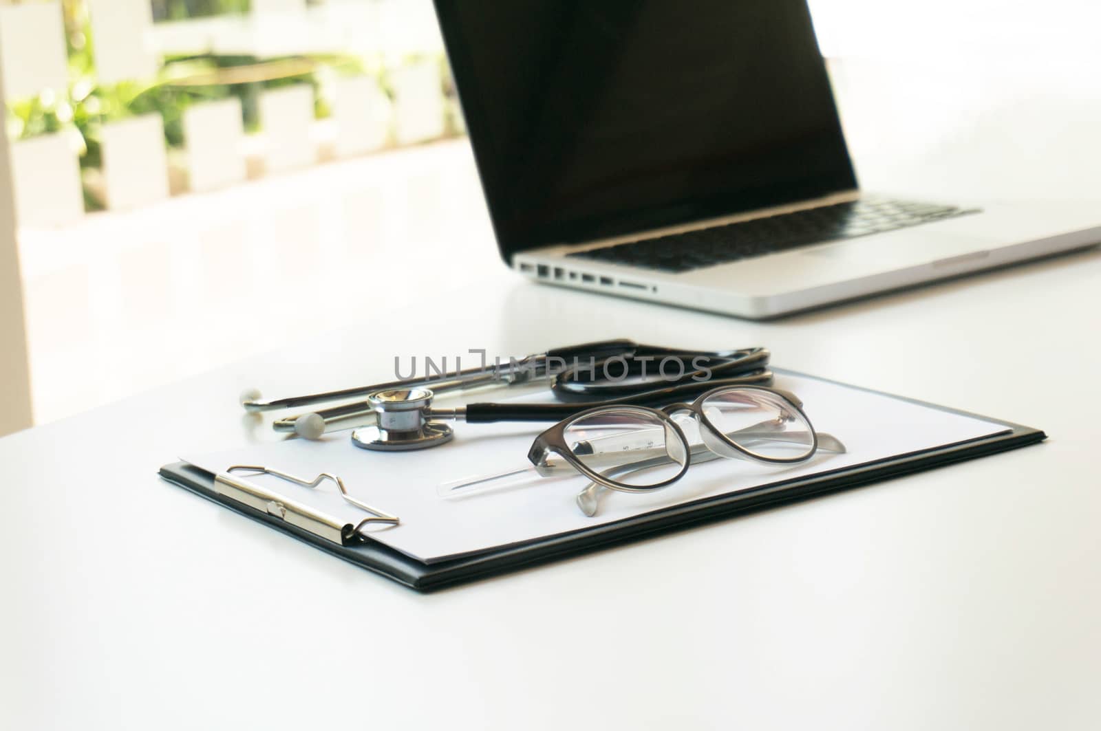 Close-up of stethoscope, paper, laptop on doctor table. selectiv by peandben