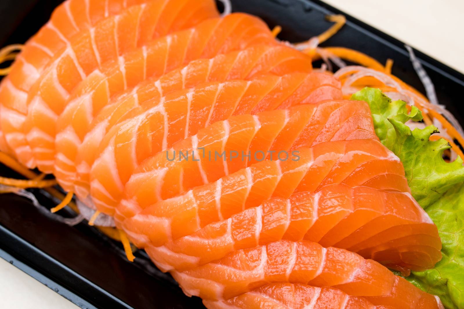 sliced salmon sashimi on black plate by antpkr