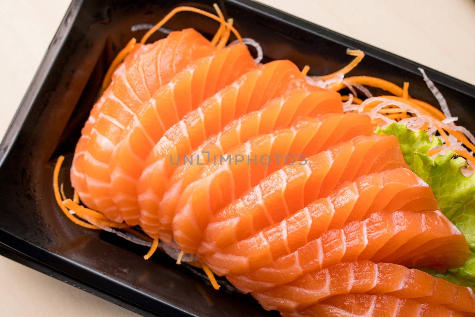 sliced salmon sashimi on black plate by antpkr