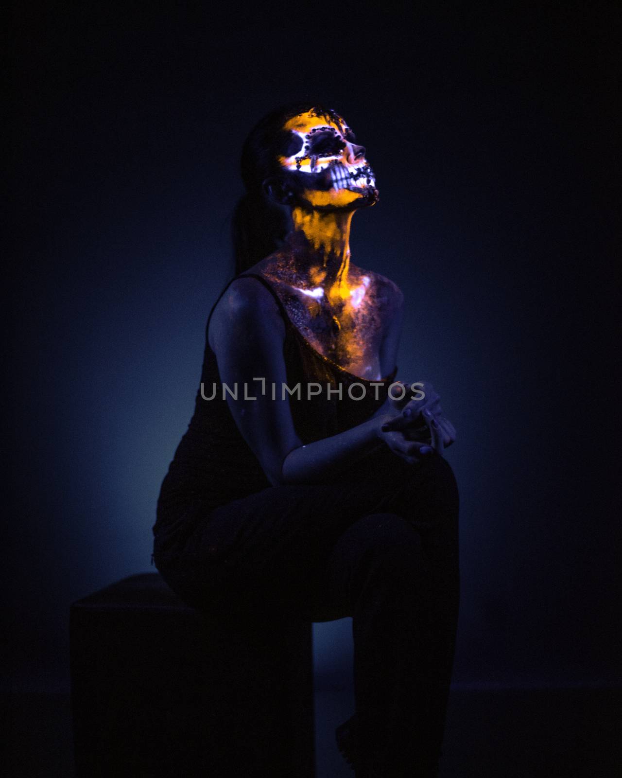 Girl's Face painted in fluorescent UV colors and looks like Neon Glowing Skull