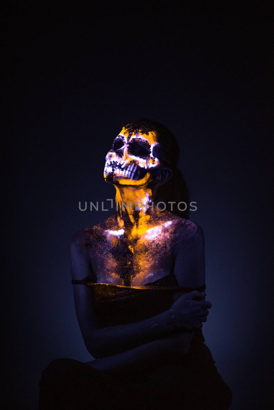 Girl's Face painted in fluorescent UV colors and looks like Neon Glowing Skull