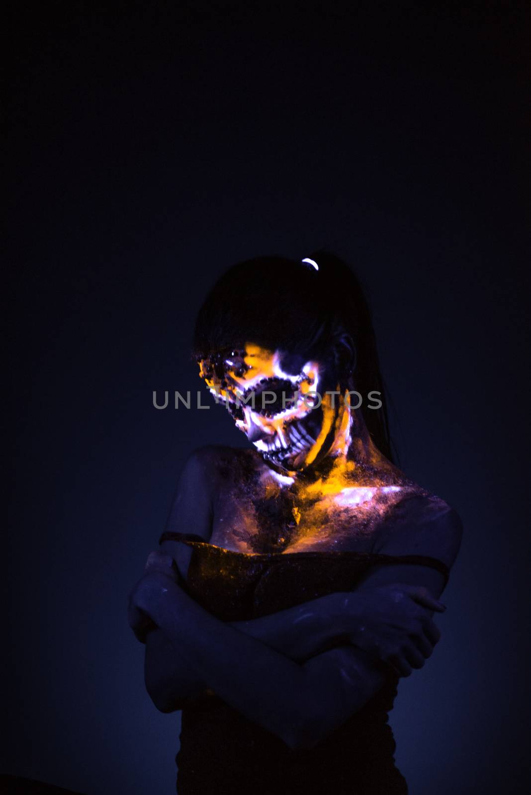 Girl's Face painted in fluorescent UV colors and looks like Neon Glowing Skull