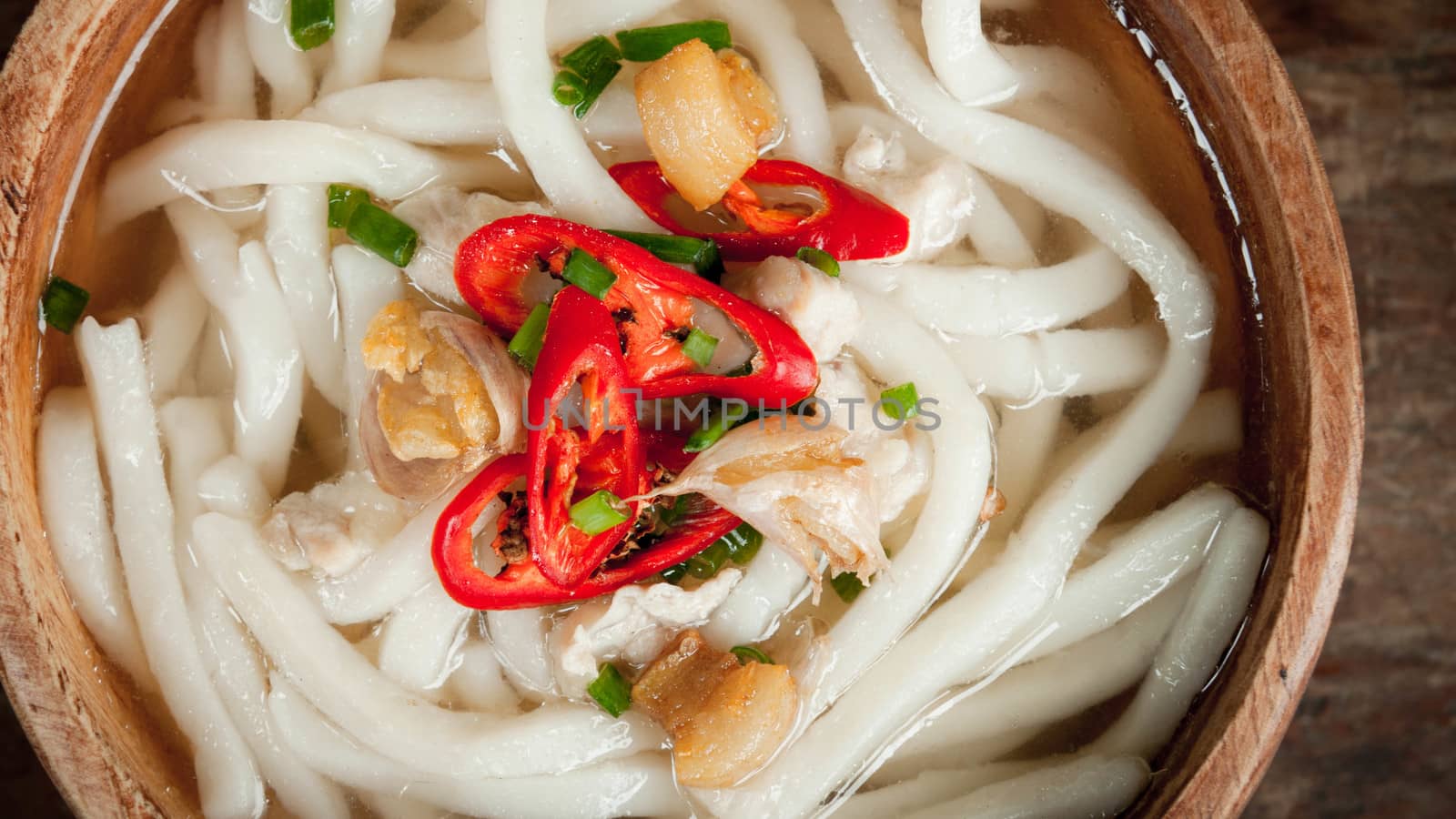 closeup of udon noodle in wood bowl on wooden floor background