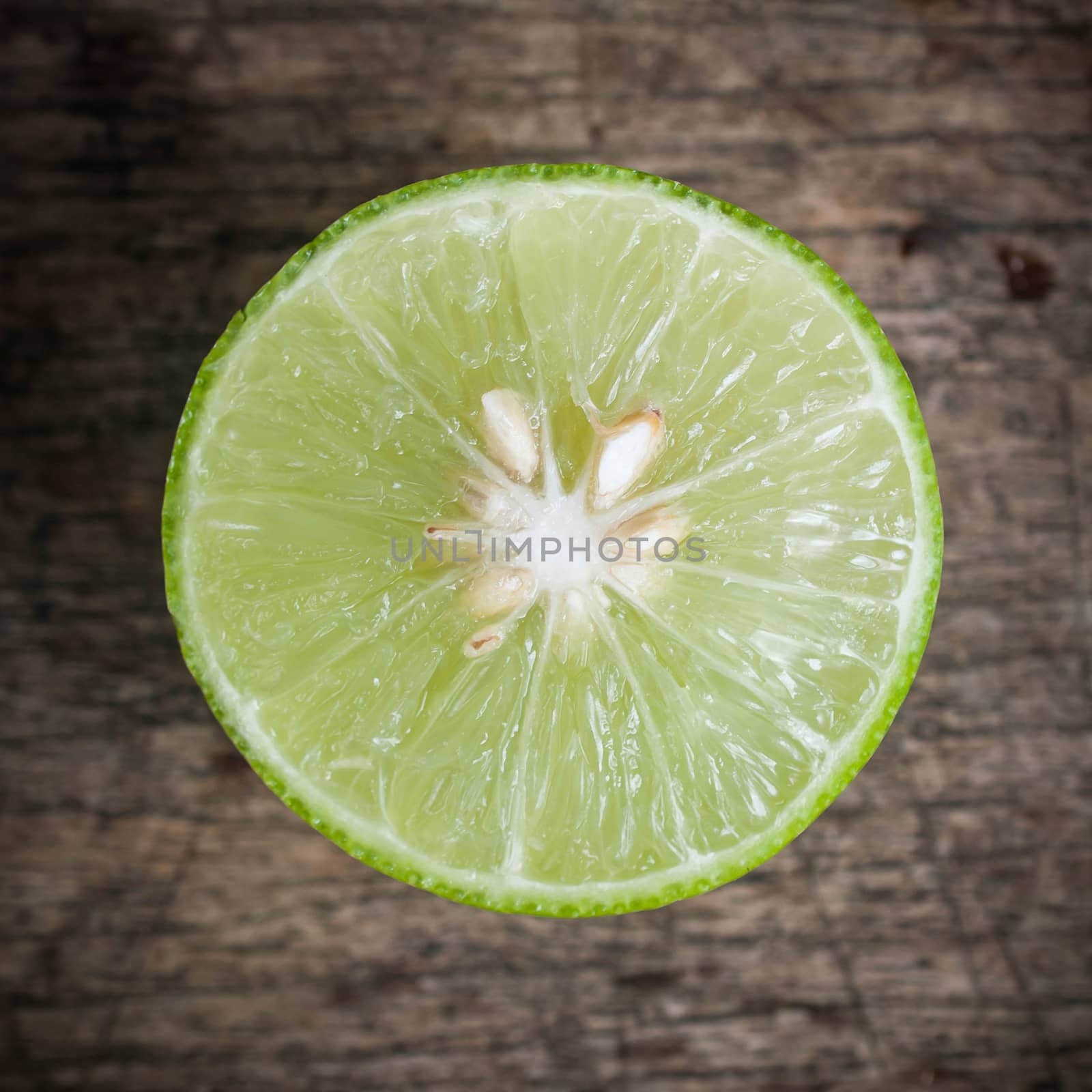 Green Lemon cut on wooden background