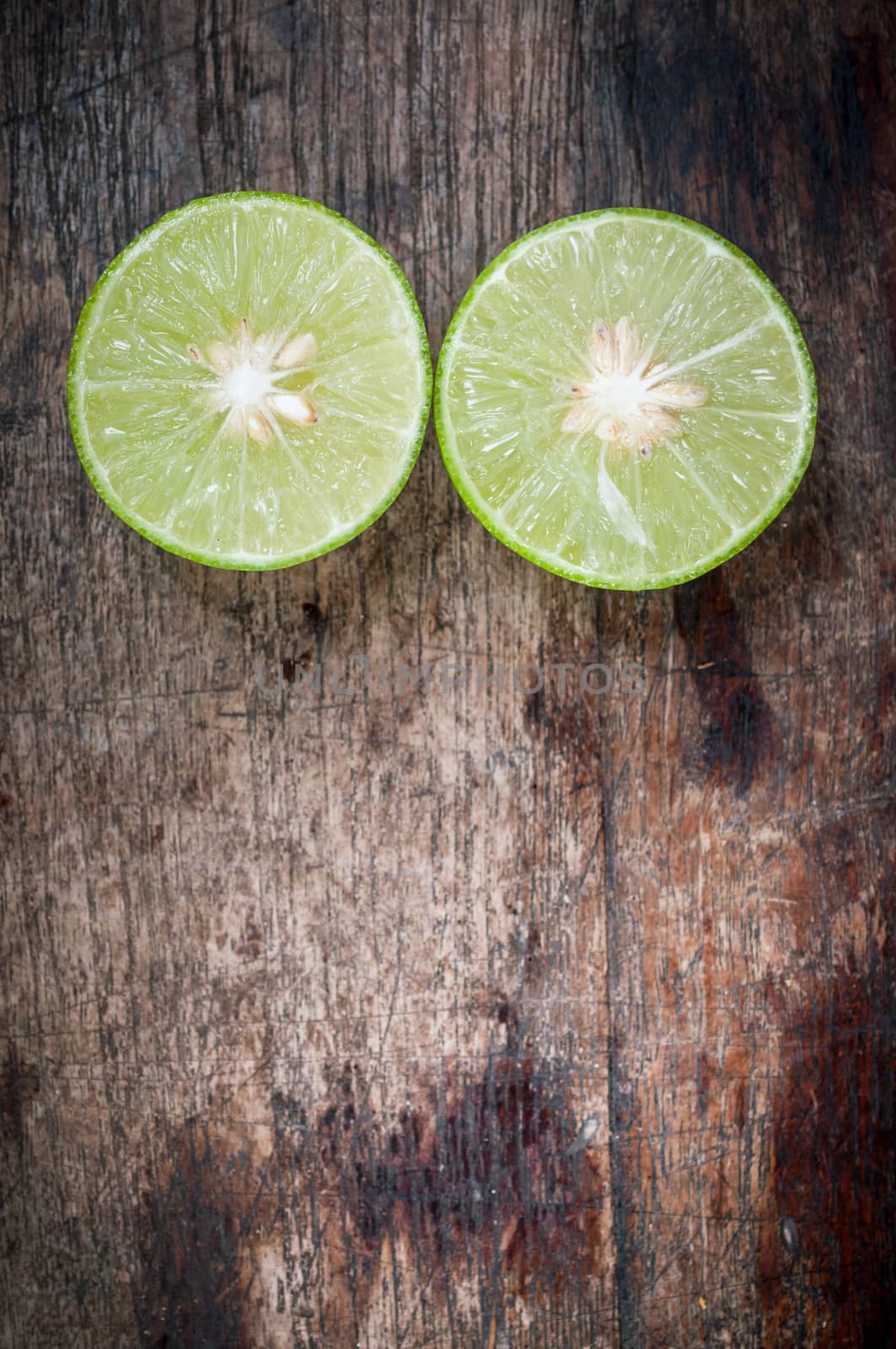 Green Lemon cut on wooden background