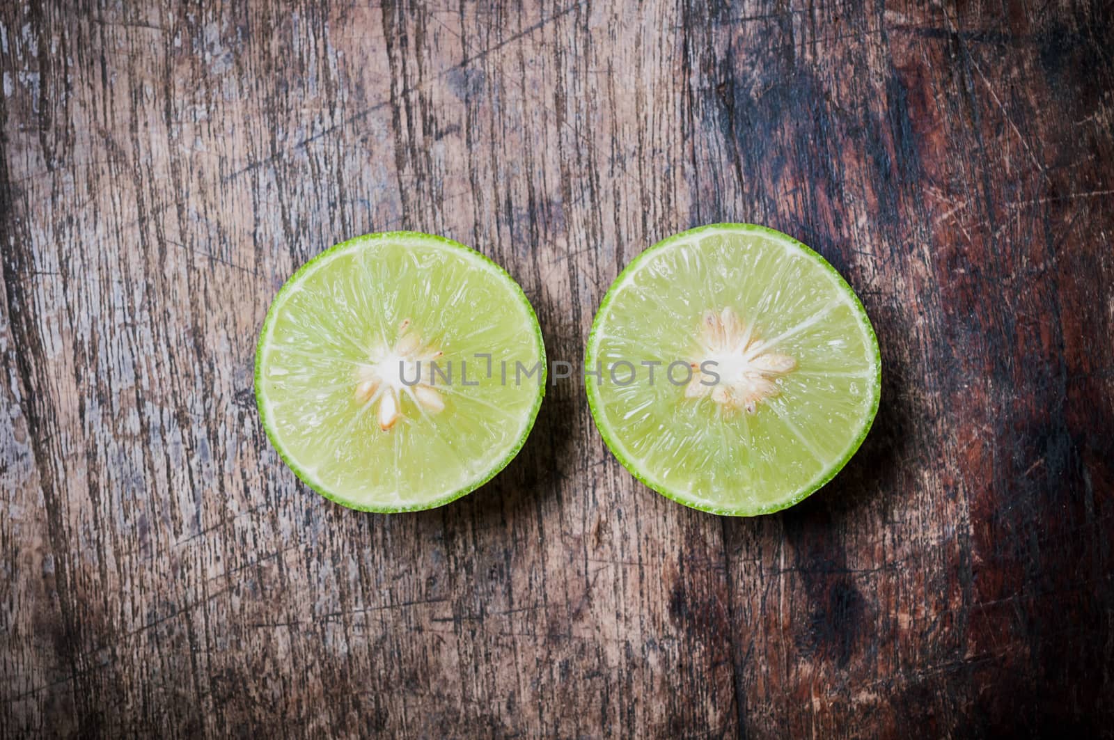 Green Lemon cut on wooden background