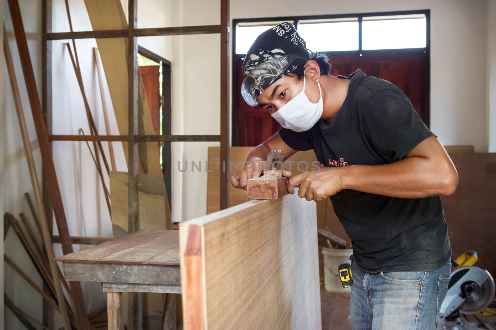 carpenter man use planer making a wood door by sayhmog