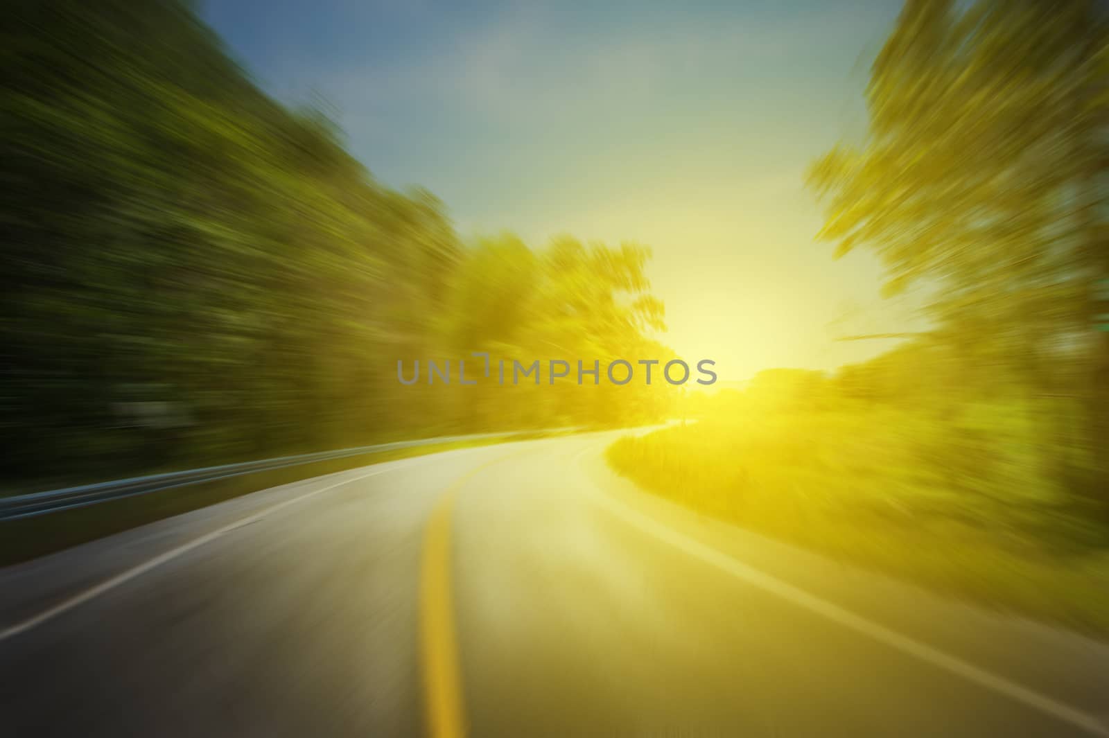Asphalt road in motion blur of speed effect through and sunset