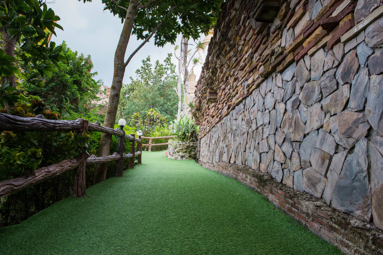 Green grass street and stone wall