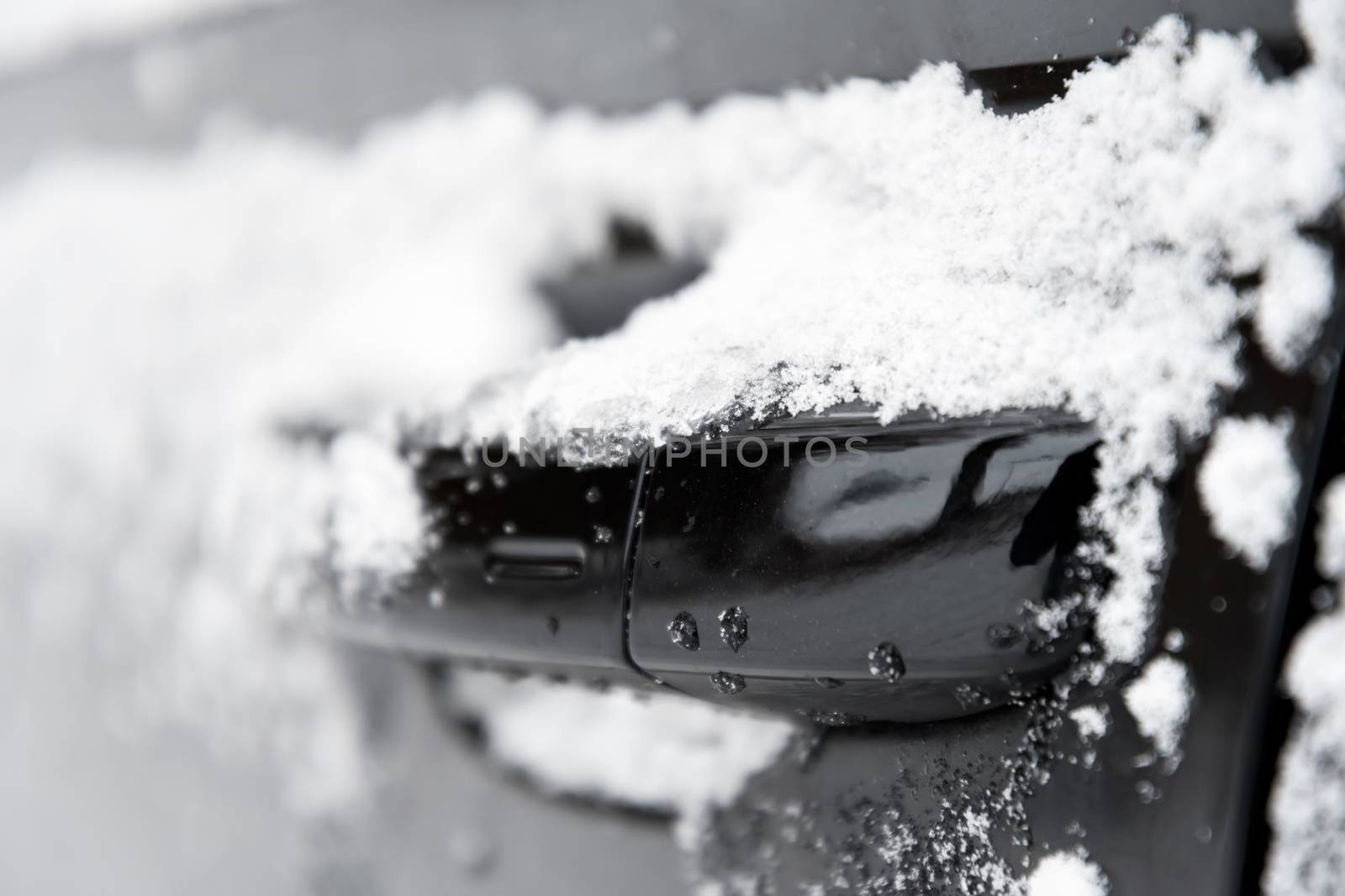 closeup of a doorknob of a car with snow in winter
