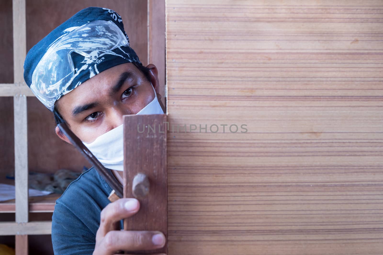 Young male carpenter take a planer with wood in workshop